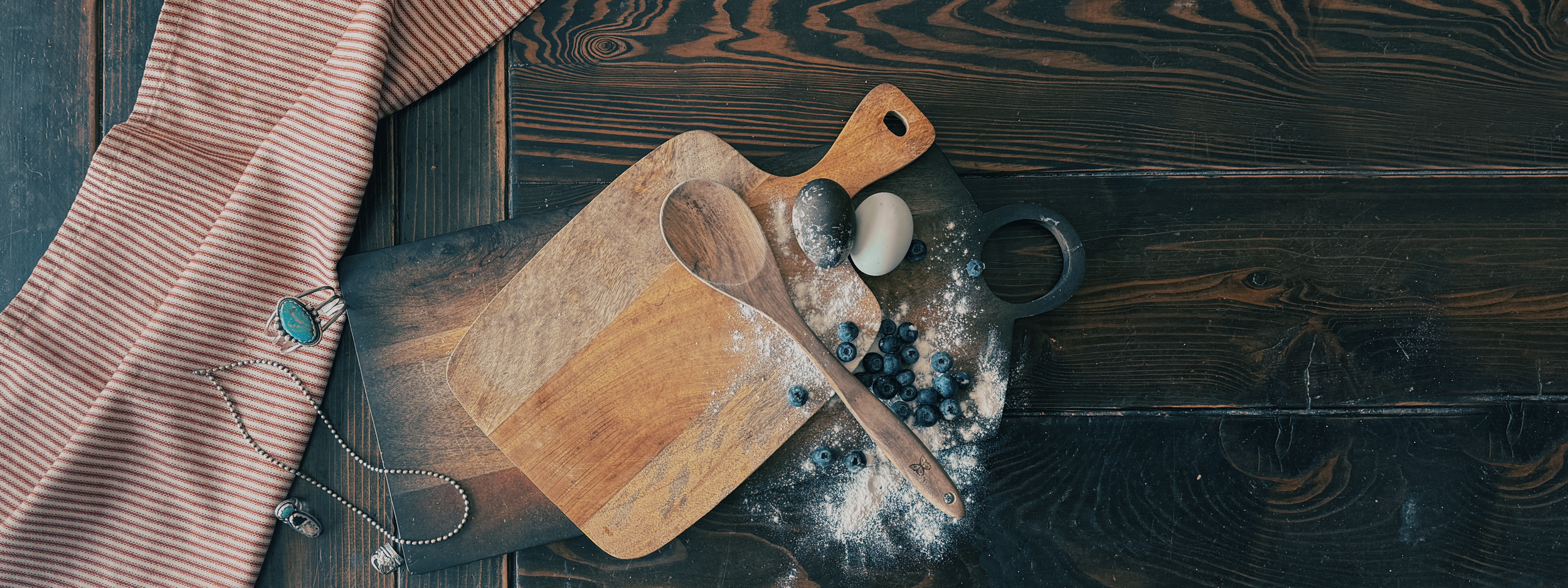M7 Trading Post: Handmade Homestead bakery goods including large gourmet cookies and 6 oz brioche rolls on a rustic red and white towel.