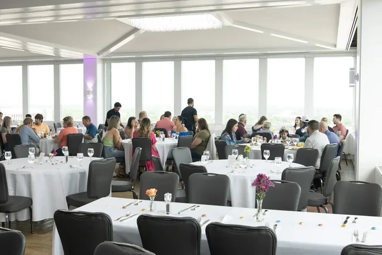 Guests dining at round tables in a bright banquet hall.