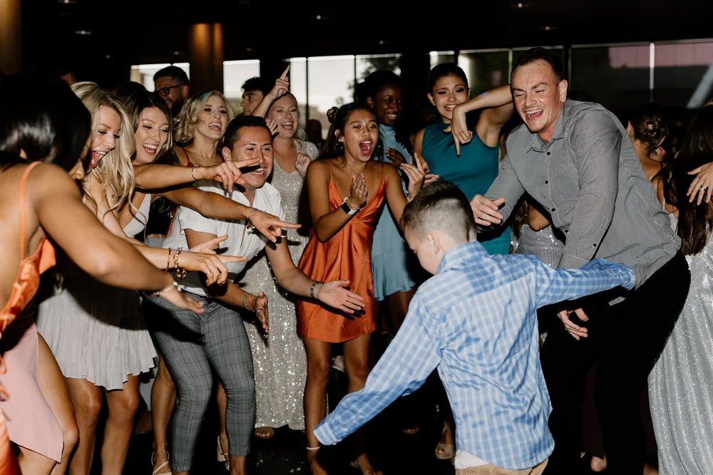 Group of people celebrating and dancing at a party or wedding reception.