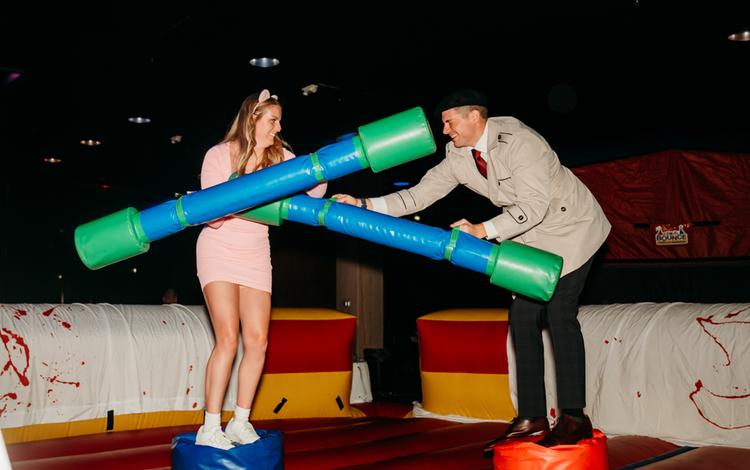 Two guests playing a game with large foam tubes on an indoor track.