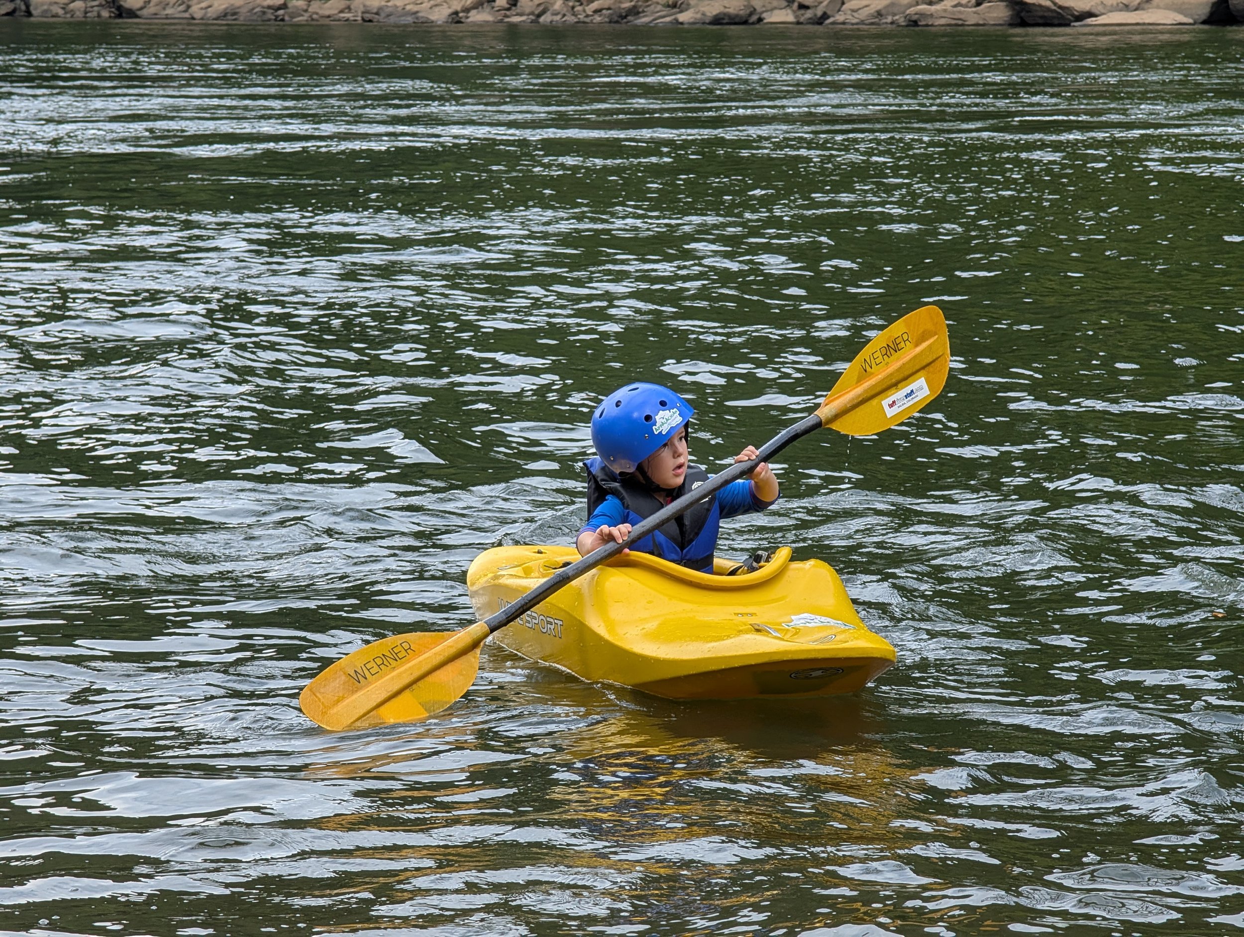 young kid testing out a wavesport kayak and a Werner Paddle