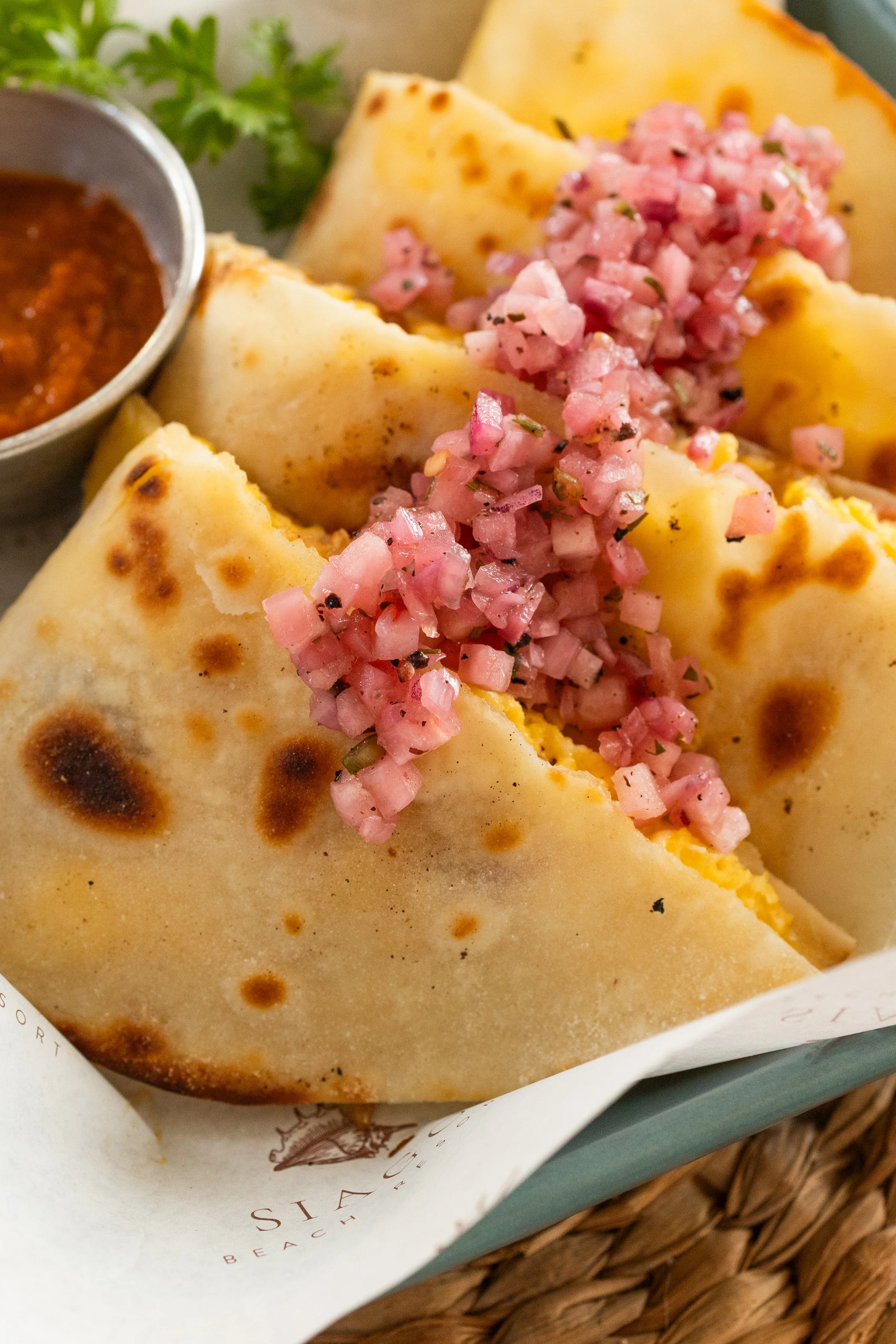 Three cheese taco with pink diced onions and a side of salsa.