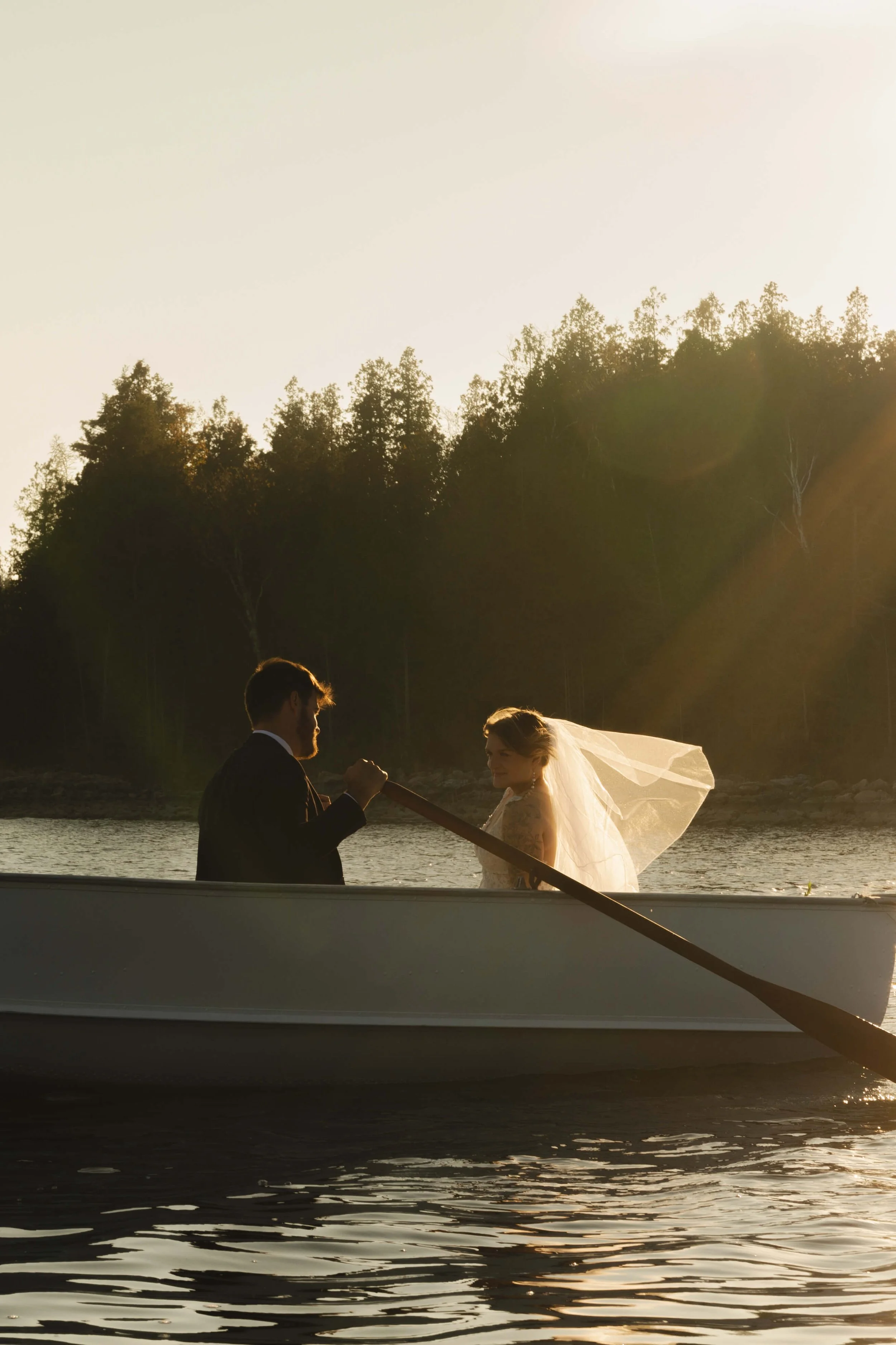 A bride and groom on a boat during sunset.