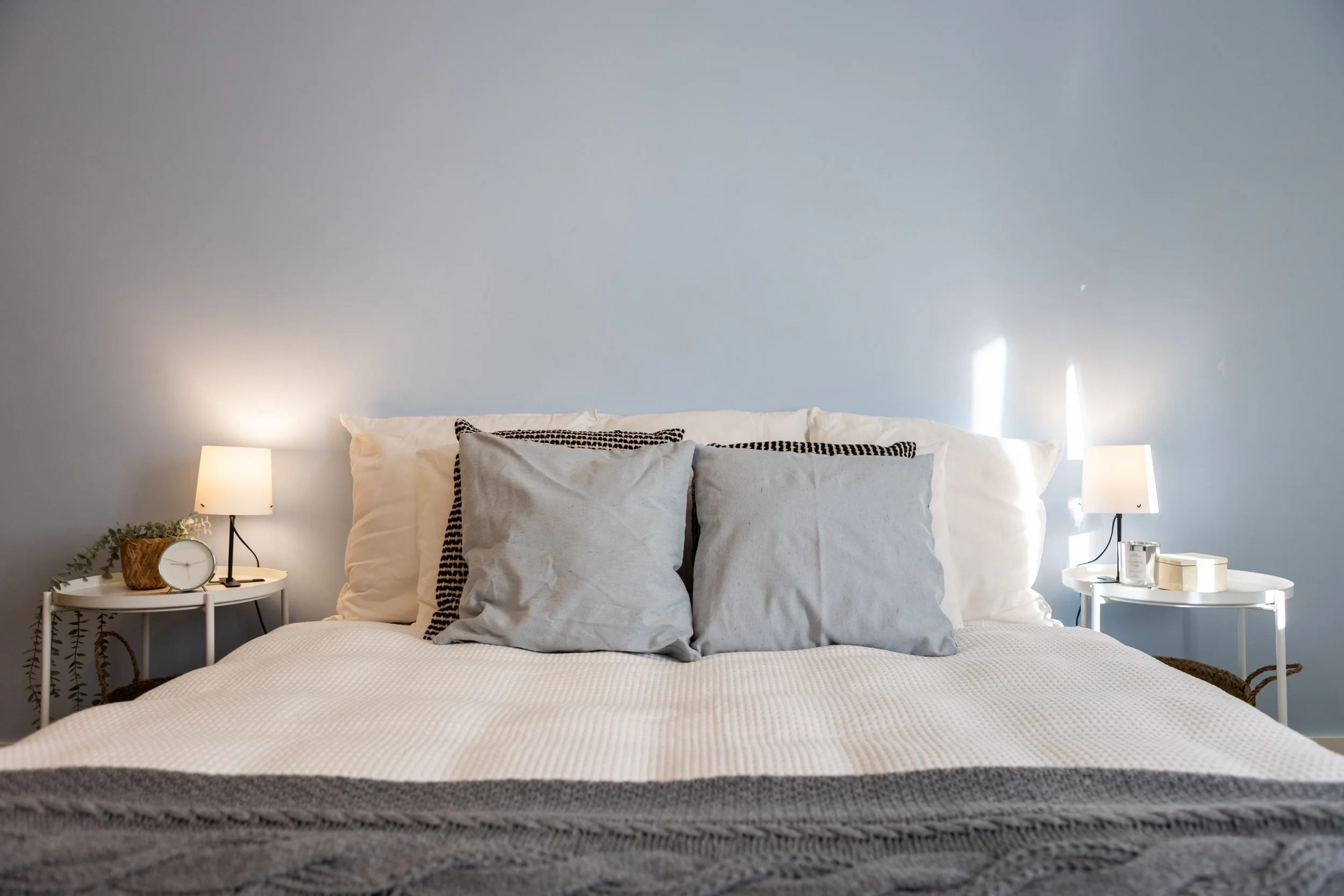 quarto de apartamento t3 parque das nações com parede azul clara e homestaging moderno com têxteis neutros