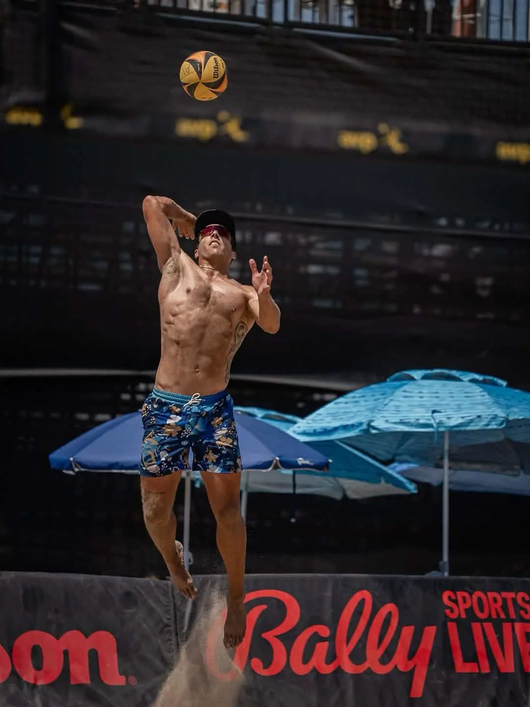 Alex Ukkelberg serving during a professional beach volleyball match