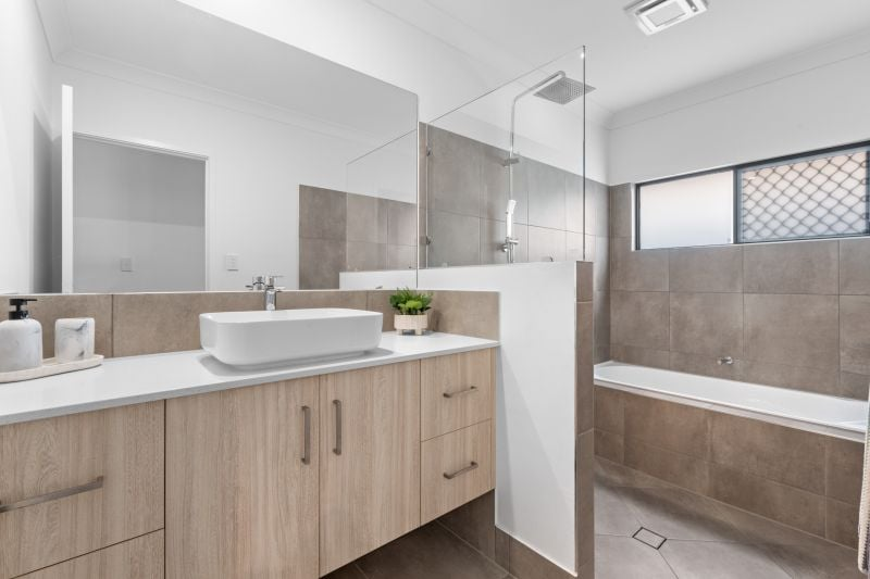 Modern bathroom with vanity, vessel sink, mirror, glass shower, bathtub, and tiled walls and floor.