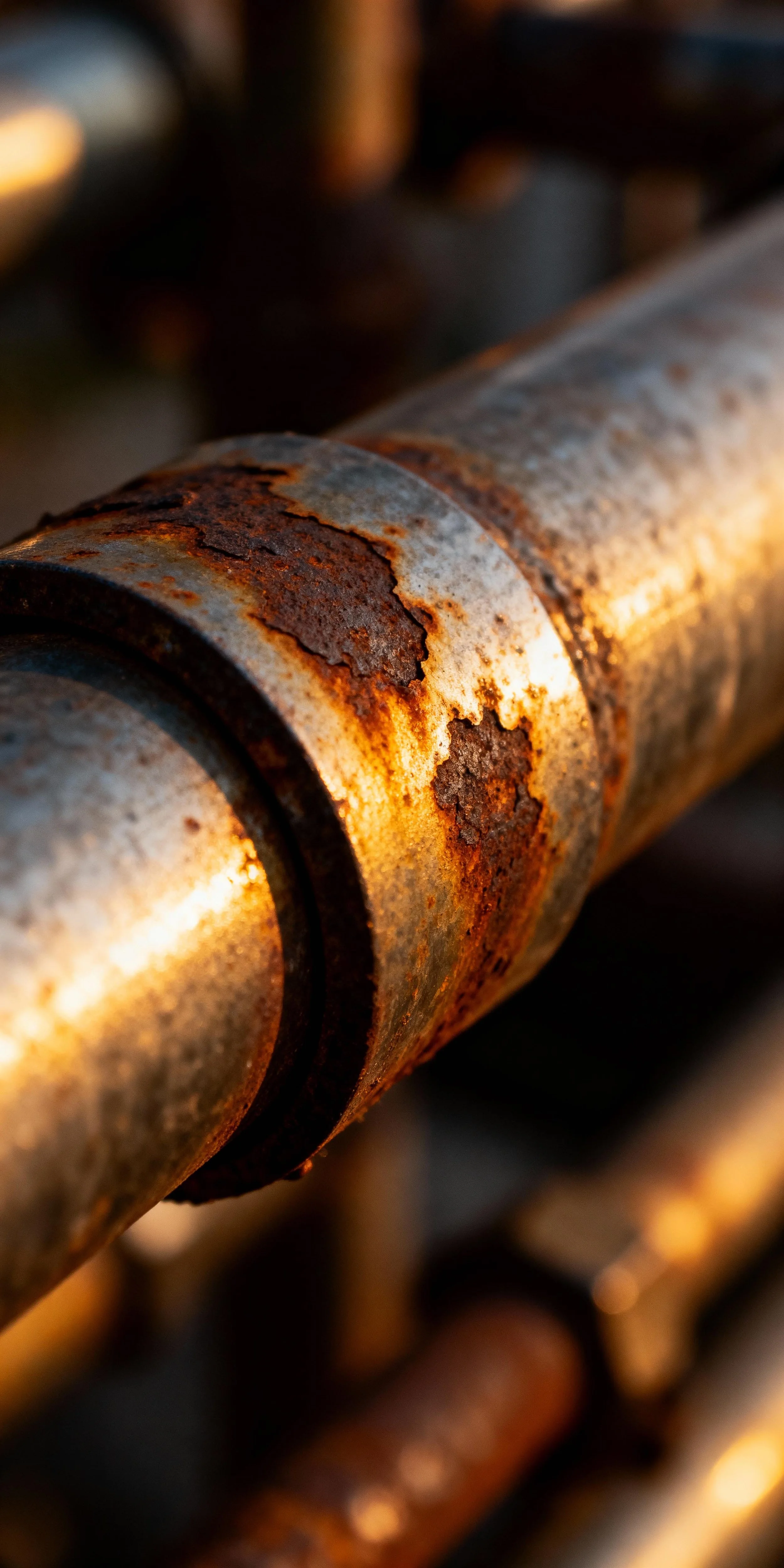 Close-up of a rusty, corroded metal pipe or cylinder with peeling paint and oxidation.