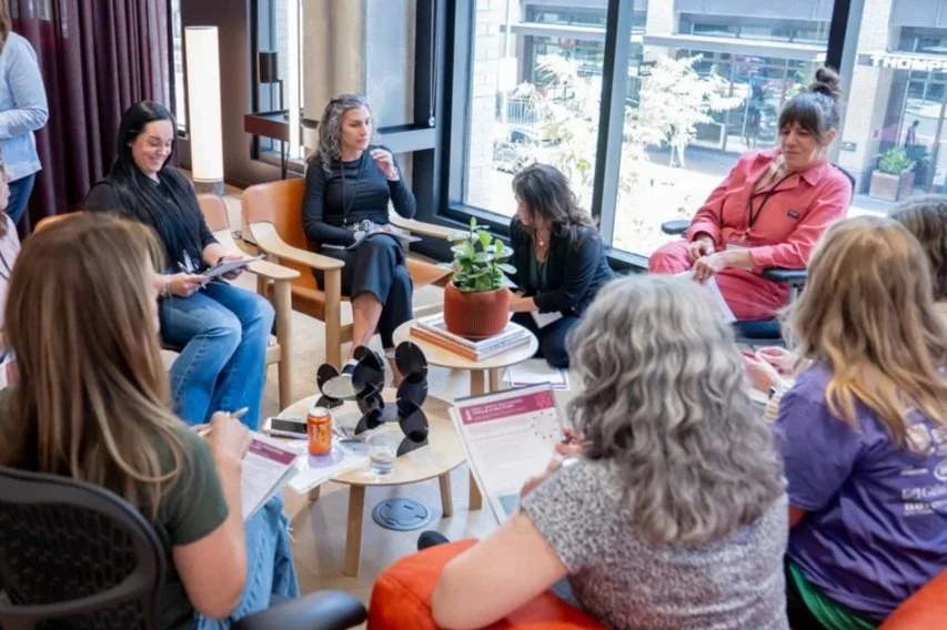 Group of women sitting in a circle in a modern office space, engaging in leadership and personal growth topics.