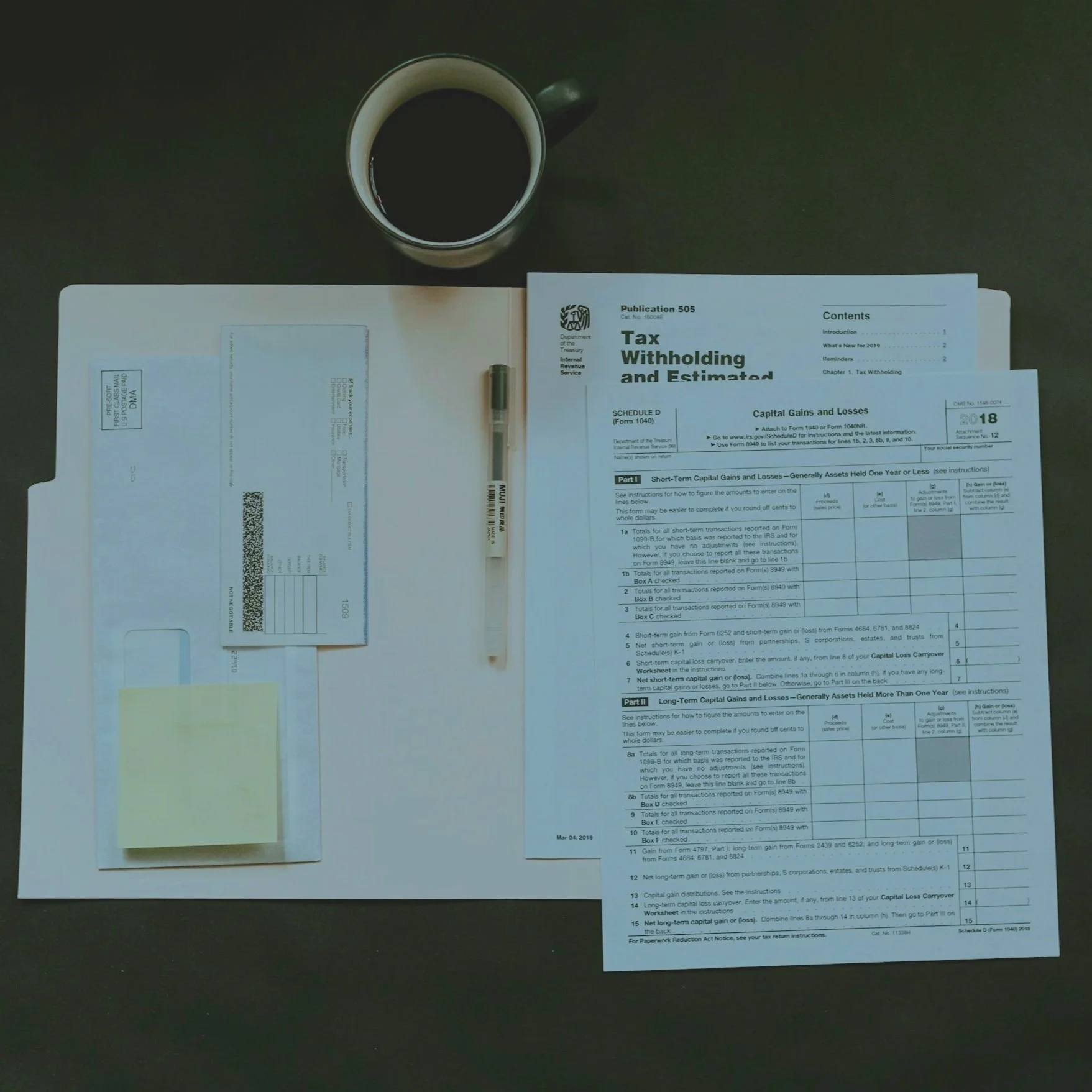 Top-down view of a desk with a coffee mug, tax paperwork, a pen, a check, and sticky notes.