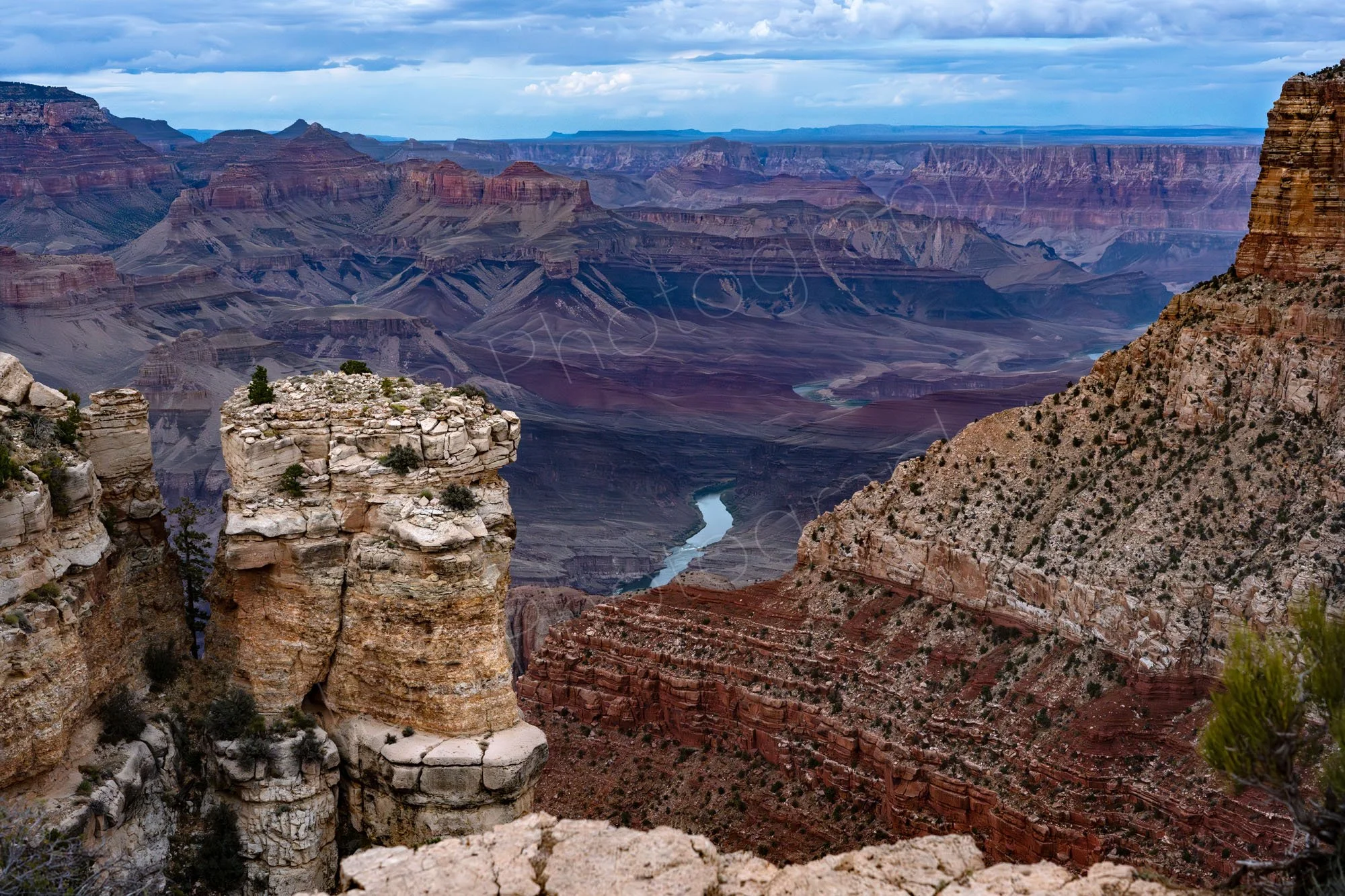 A cloudy-day sweeping view from the South Rim of the Grand Canyon Arizona, prominent eroded rock pillars in the foreground. 