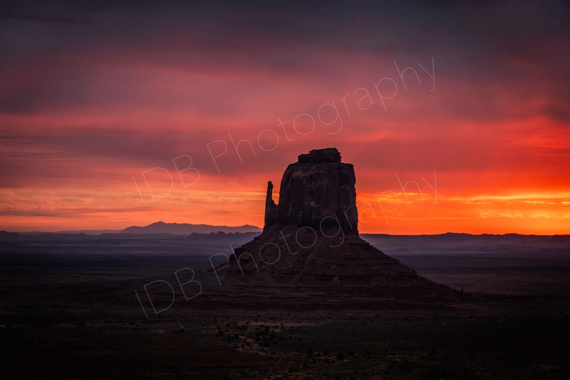 West Mitten Butte, Monument Valley, Utah at sunset. The butte is almost silhouetted against a dramatic red sky.