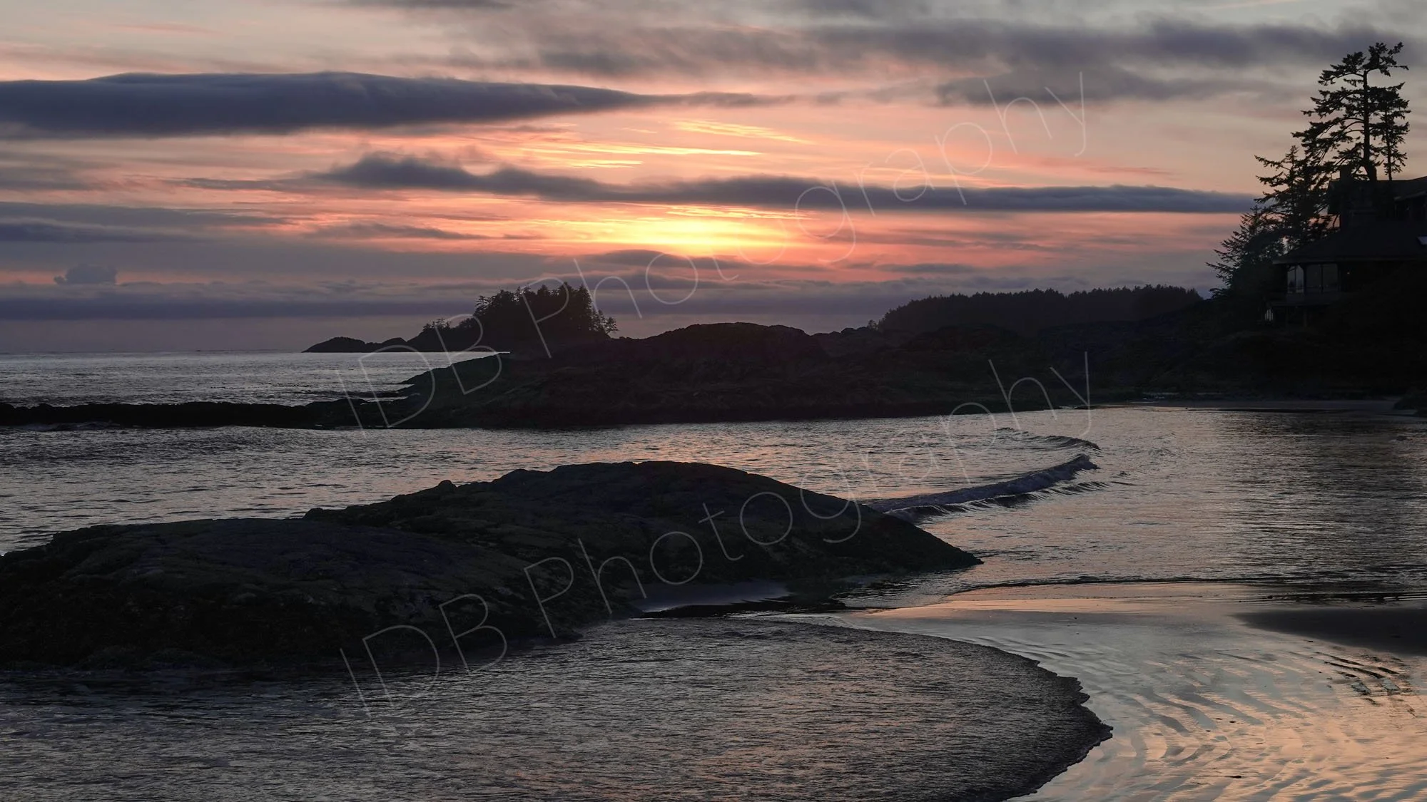 A sunset over the rugged rocky shores and sandy tidal pools of Chesterman Beach near Tofino , Vancouver Island, BC.
