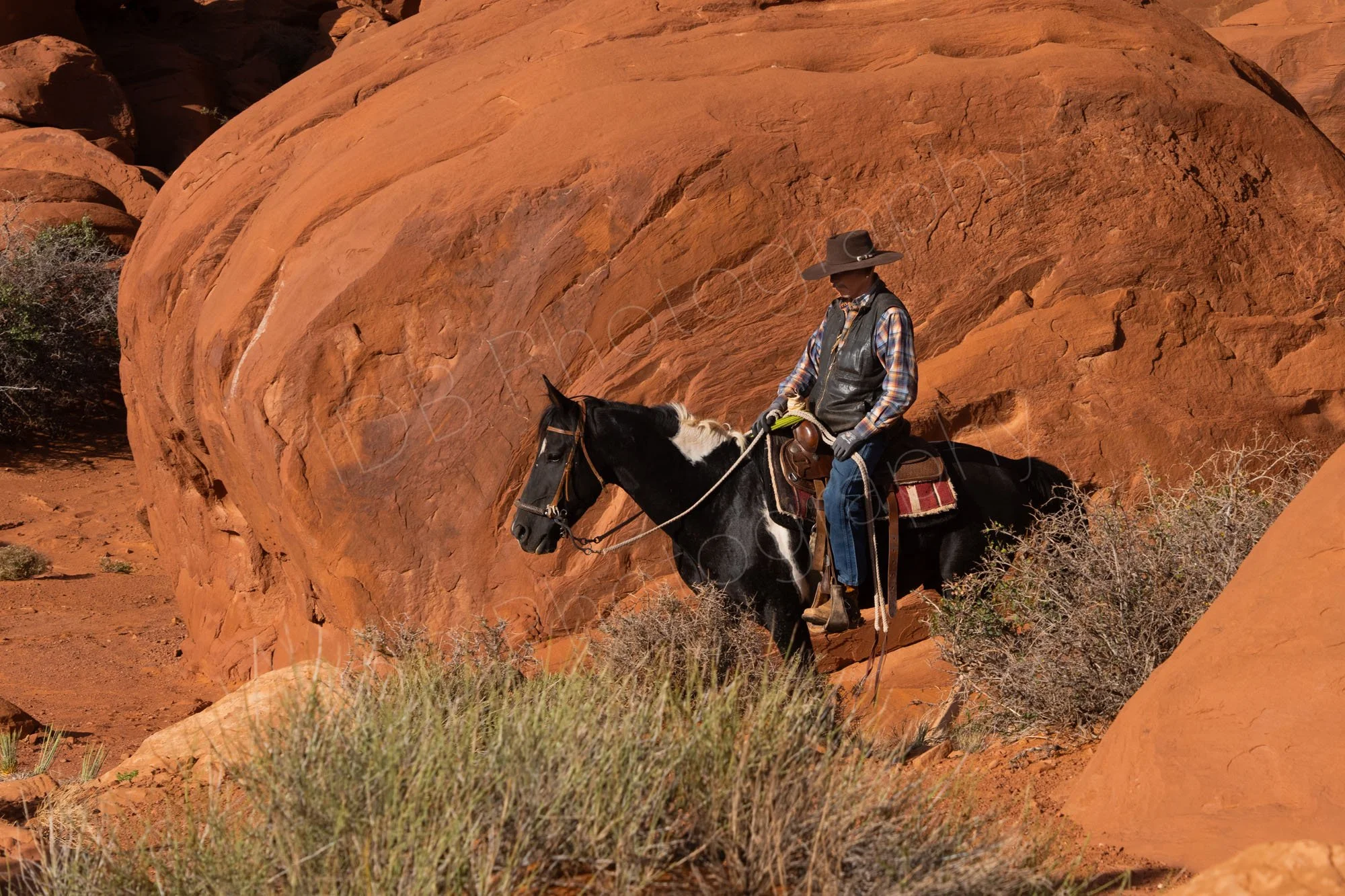 A male Navajo rides his horse amongst the red-orange boulders at Monument Valley Navajo Tribal Park, Utah.
