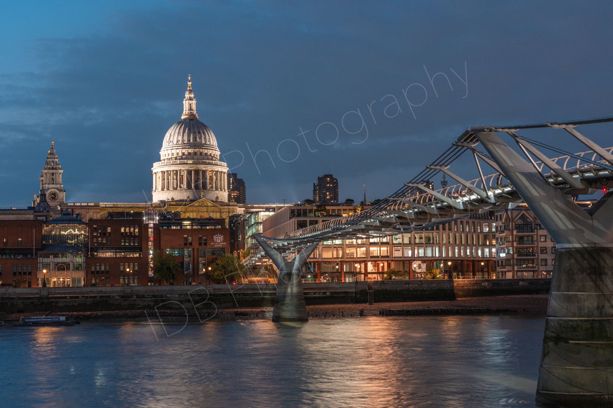 A late evening view across the Thames with the Millenium Bridge and the dome of St Paul's Cathedral, with subtle water reflections.