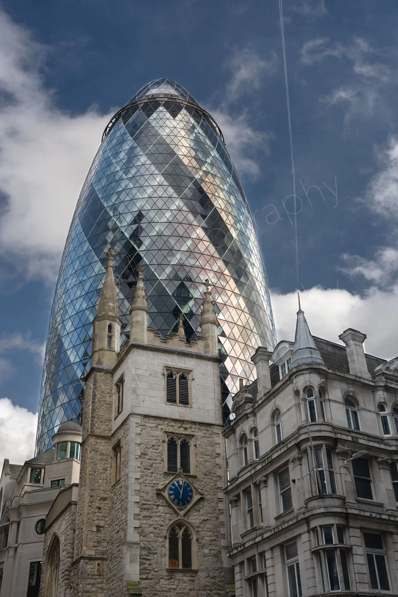 The Gherkin skyscraper behind St Andrew Undershaft Church.  A plane contrail can be seen appearing to originate from a neighbouring corner spire  akin to a magic wand.