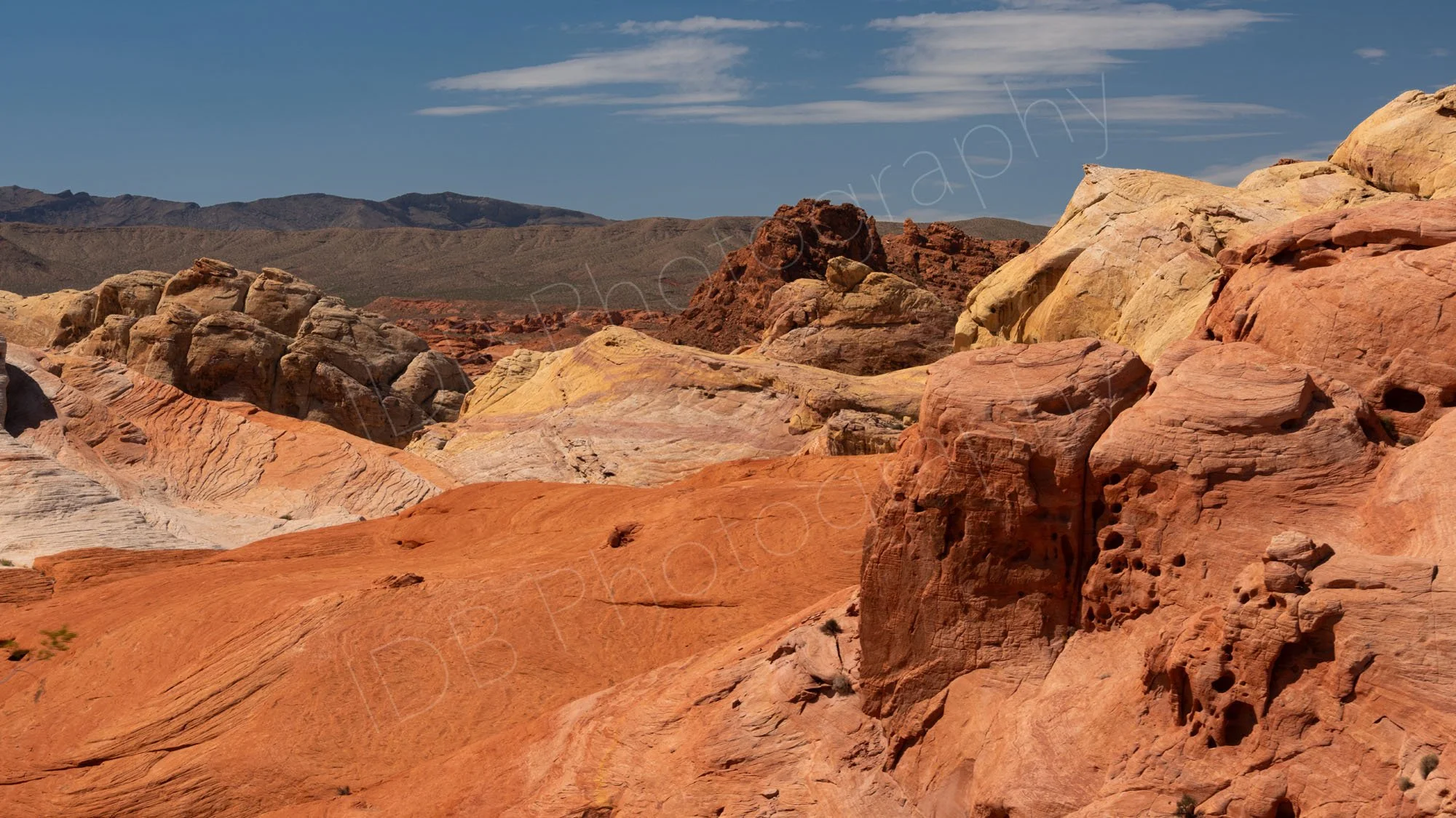 A abstract mix of rock shapes and colours  ranging from dark brown, though reds to buff with a cloudy blue sky in  Valley of Fire, Nevada, 