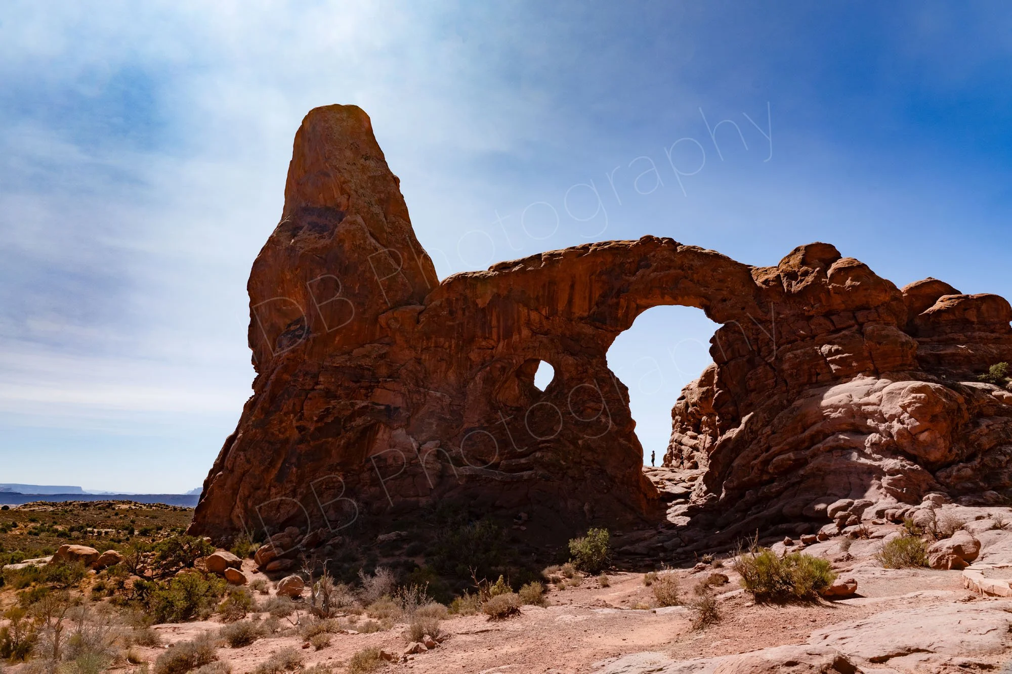 Turret Arch in Arches National Park, Moab, Utah, USA  with a person seen at the base. Nice positioning of clouds around the spire. 