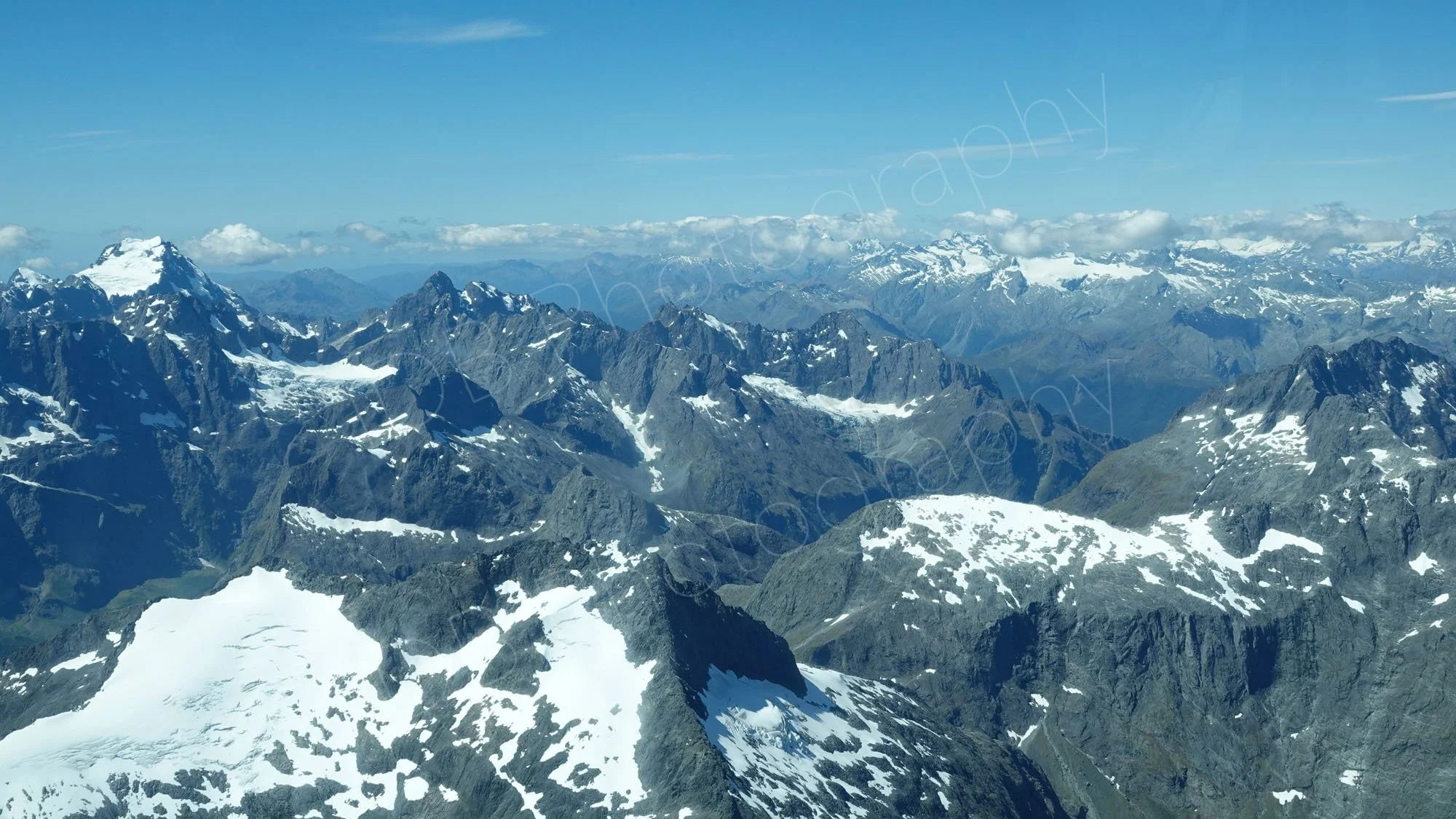 Aerial view of snow capped peaks and blue sky background near Milford Sound, Fjordlands, Southlands, New Zealand.
