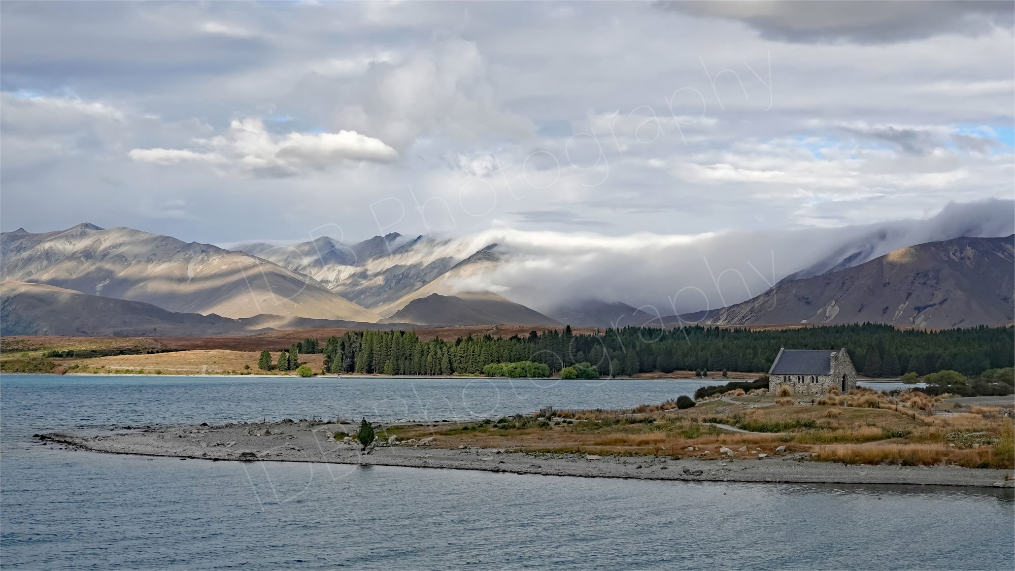 Lake Tekapo and the Church of the Good Shepherd, clouds rolling over the mountains, Canetrbury, New Zealand.
