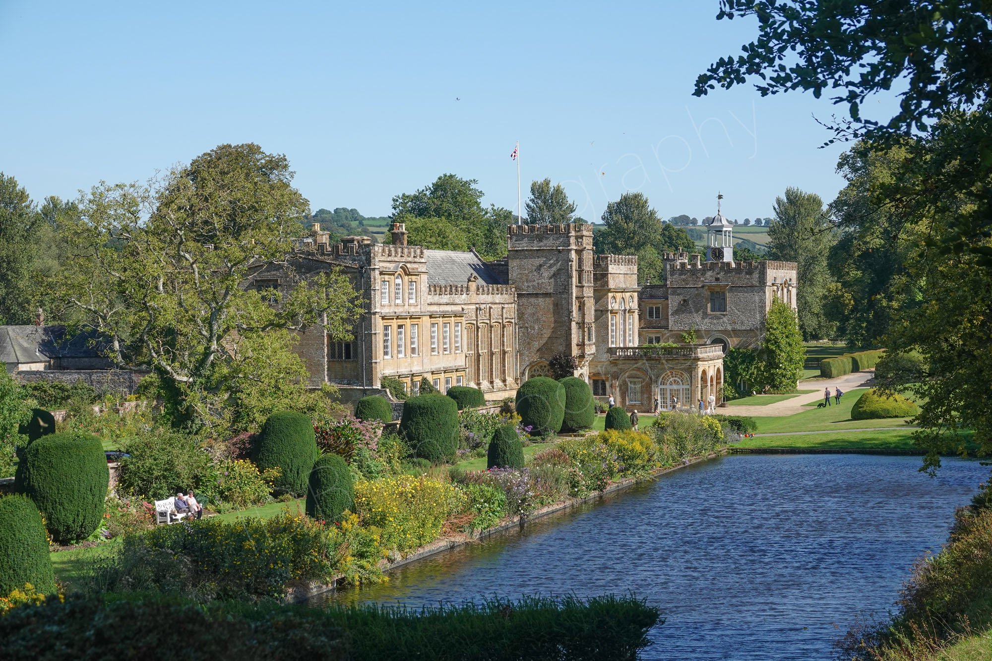 Historic house and manicured formal gardens alongside the long pond at Forde Abbey  near Chard on the Dorset-Somerset border; blue sky.