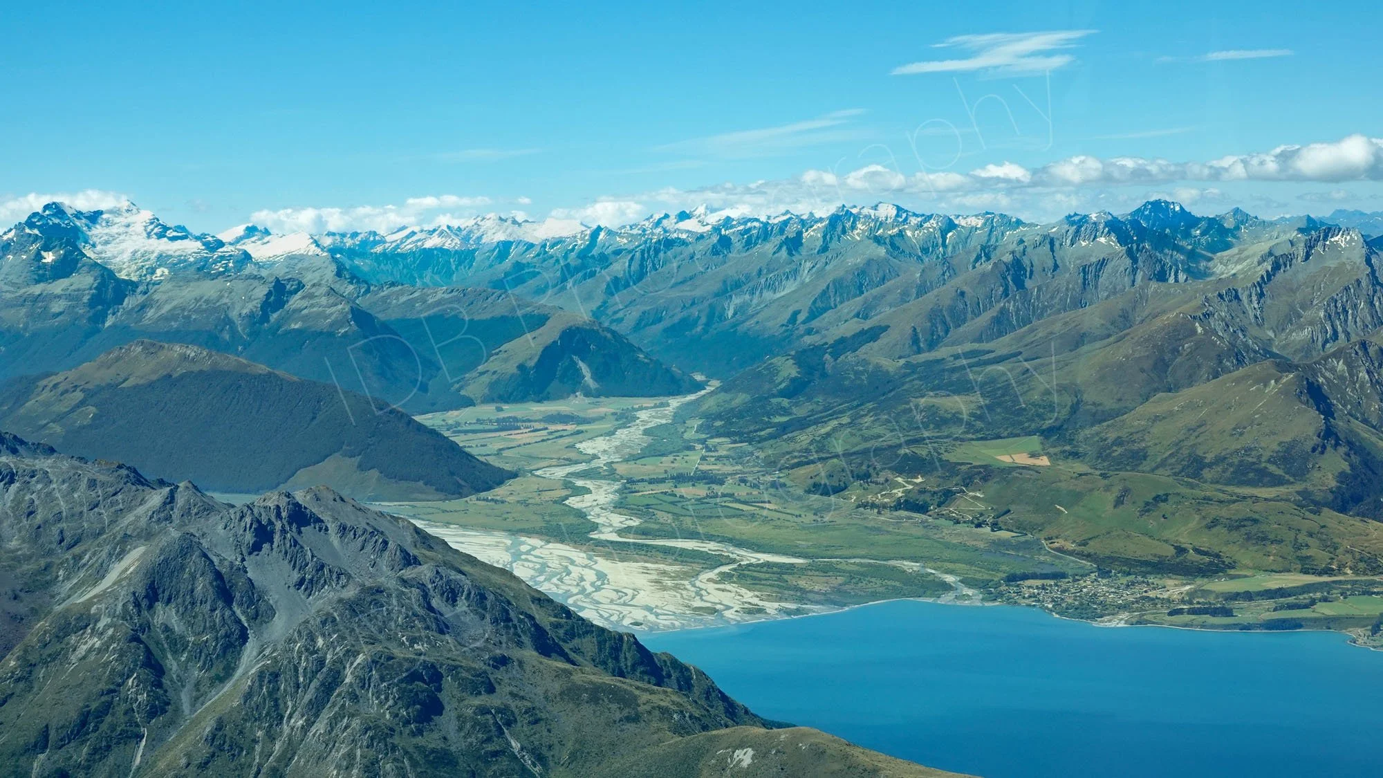 Aerial view Of Lake Wakatipu and Glenorchy village  in sunshine with snow capped mountain backdrop, Otago, NZ.