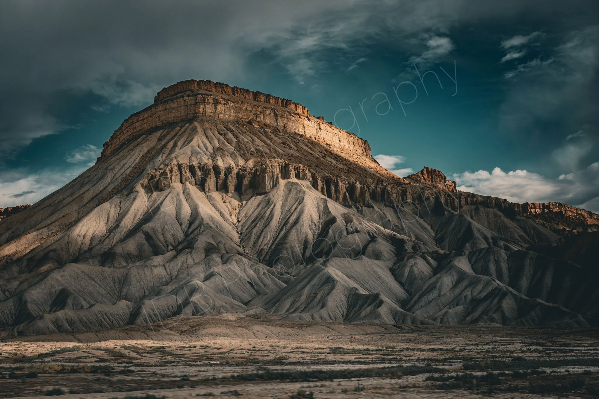 The dramatically shaped Mount Garfield, Colorado, part sunlit beneath a striking sky.