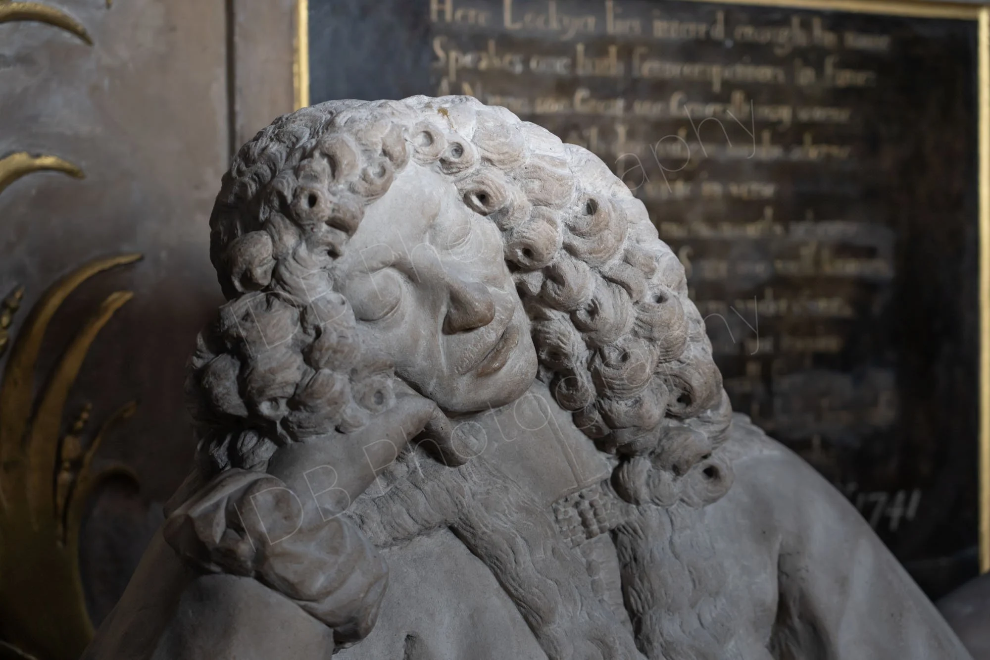A stone carving of the sleeping 17th century "quack physician"  Lionel Lockyer in Southwalk Cathedral partly illuminated by light.