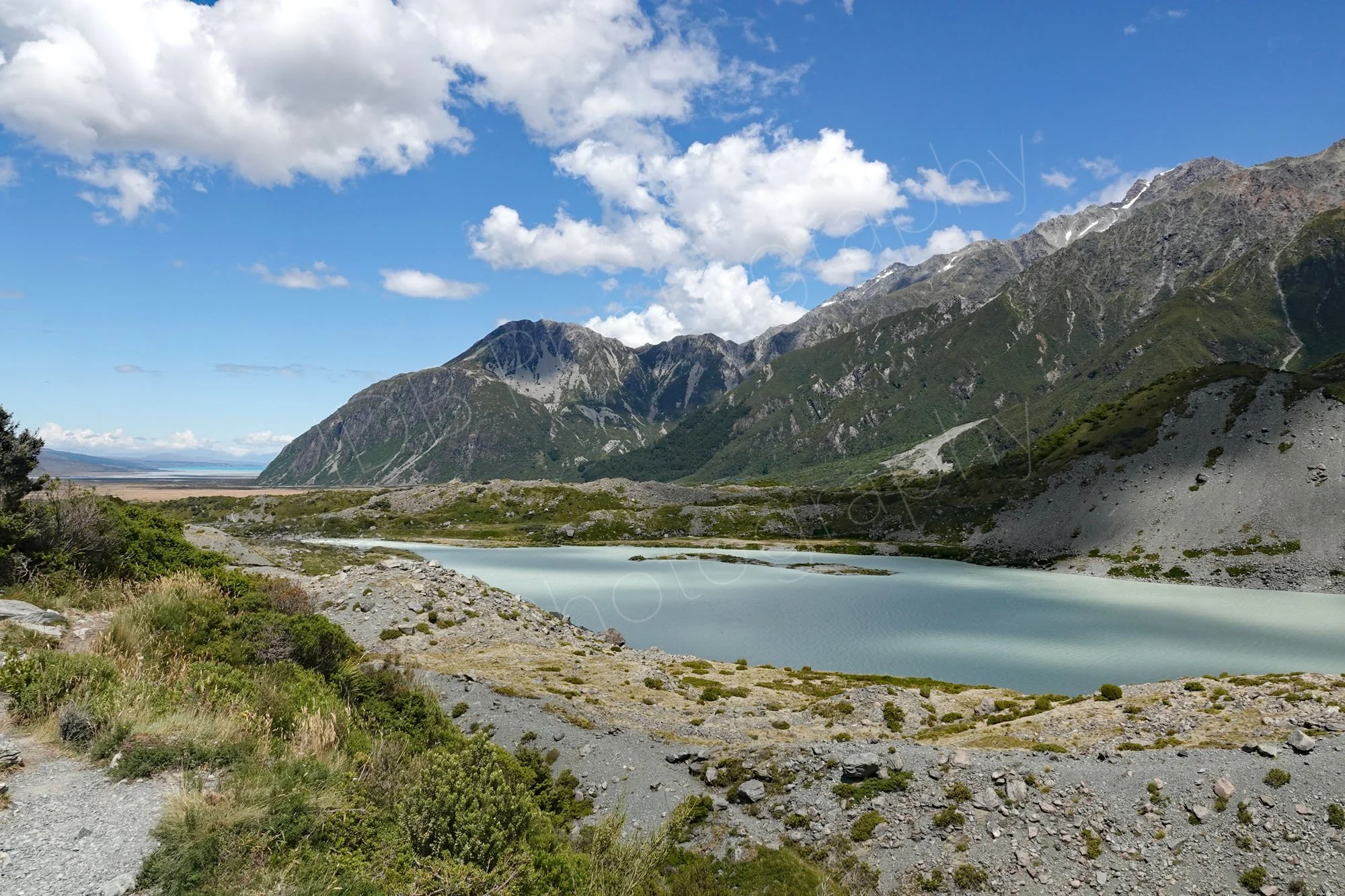  Lake, greenery and mountain view towards Lake Pukaki on the Hooker Valley track,  Canterbury, New Zealand.