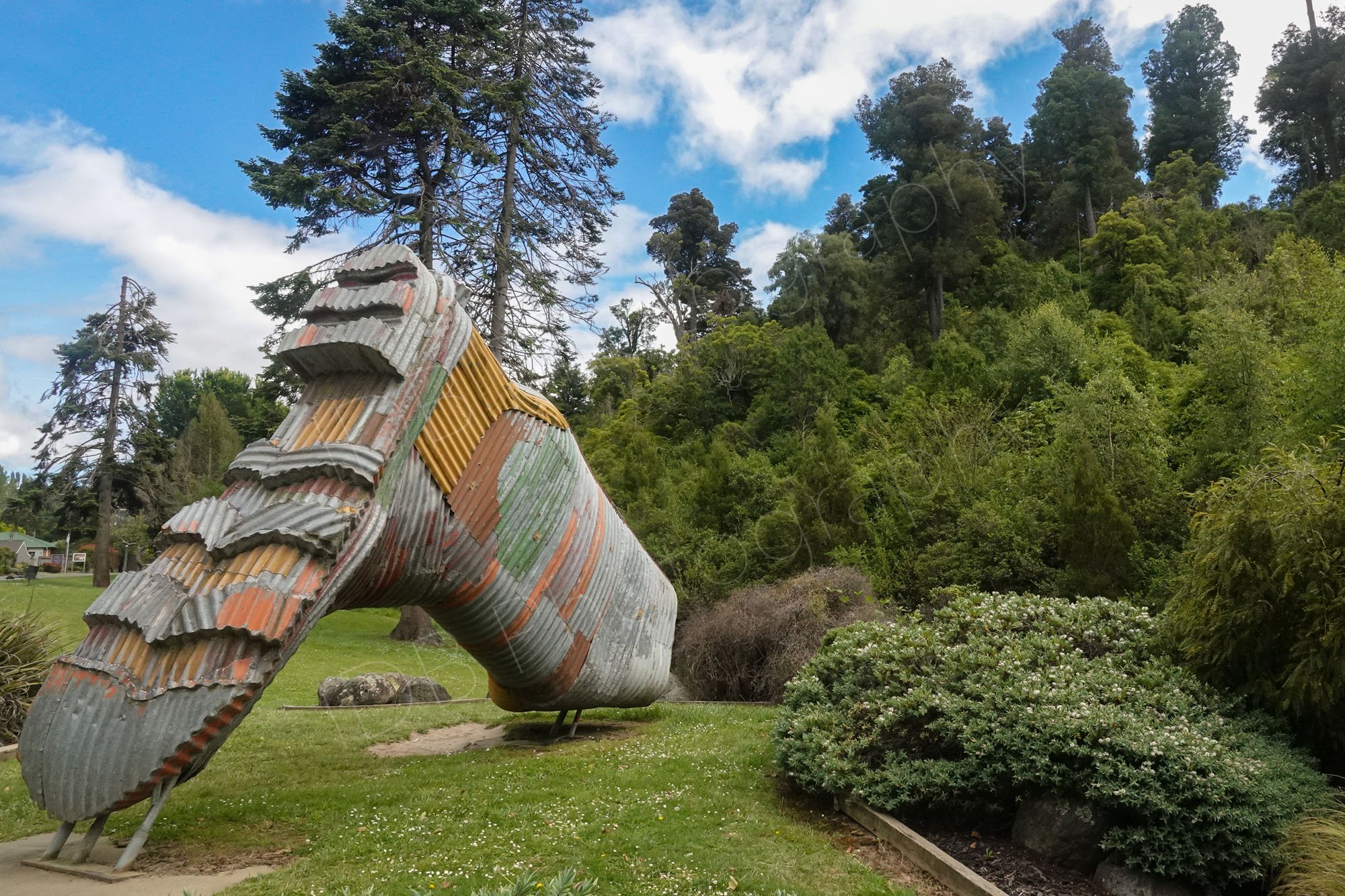 Corrugated colourful metal gumboot at Taihape, with surrounding trees and bushed in Manawatu-Whanganui region, New Zealand.