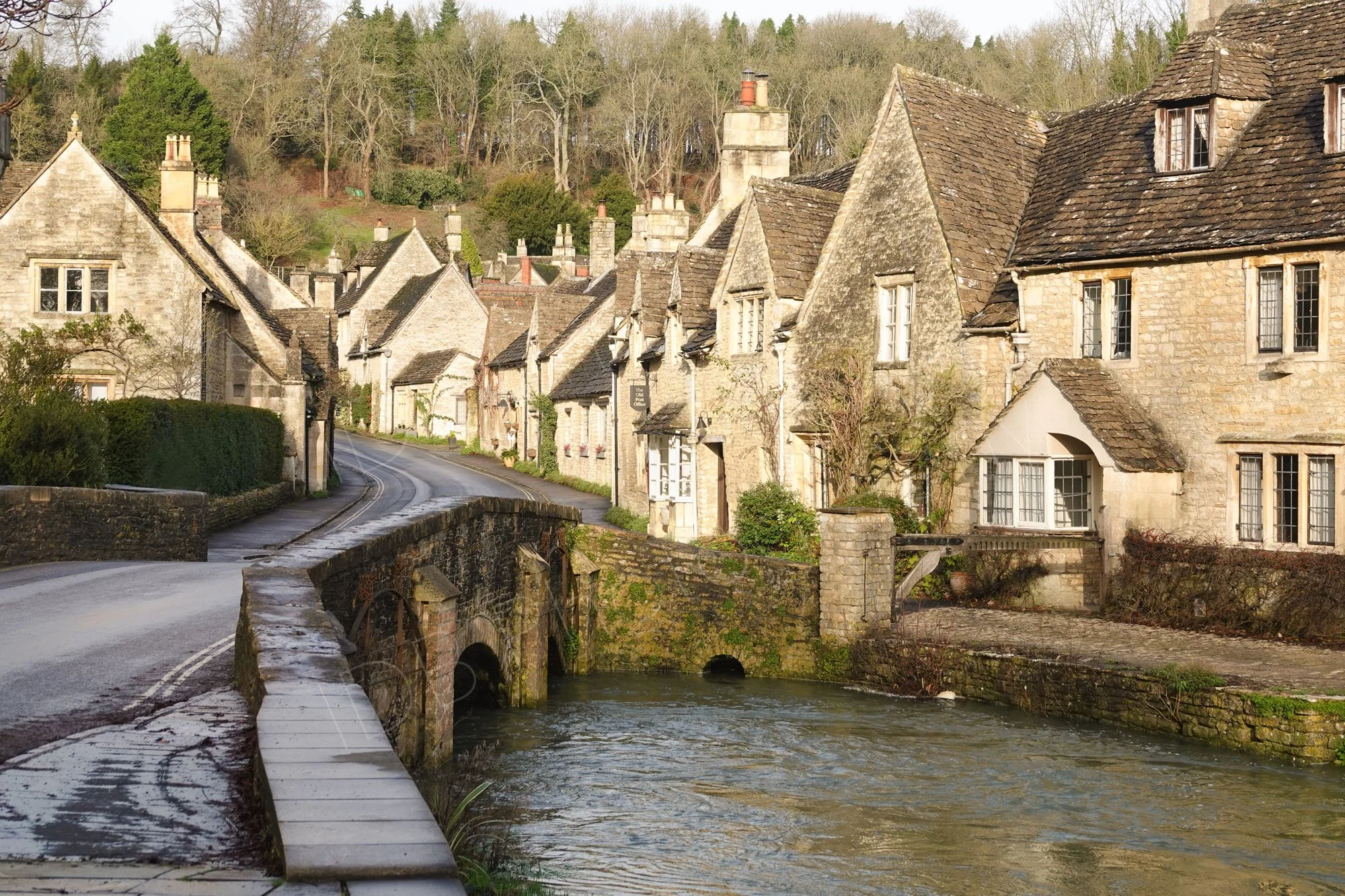 The picturesque village of Castle Combe in Wiltshire, England, with it's honey stone houses and stone bridge across the stream.