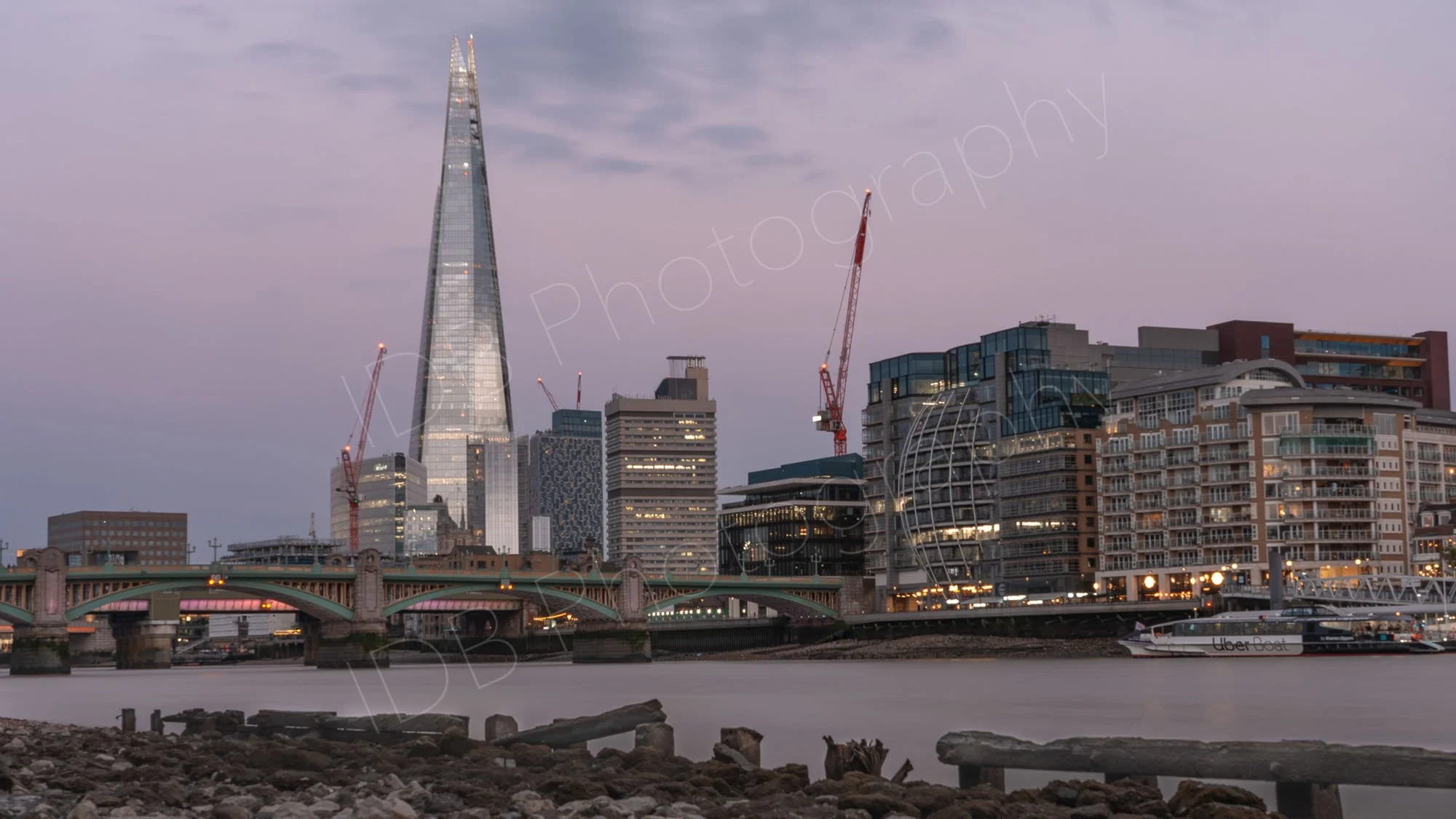 A long exposure ND filter image at twilight from the north bank of the Thames towards the Shard and Southwark Bridge, lilac hues to the sky.