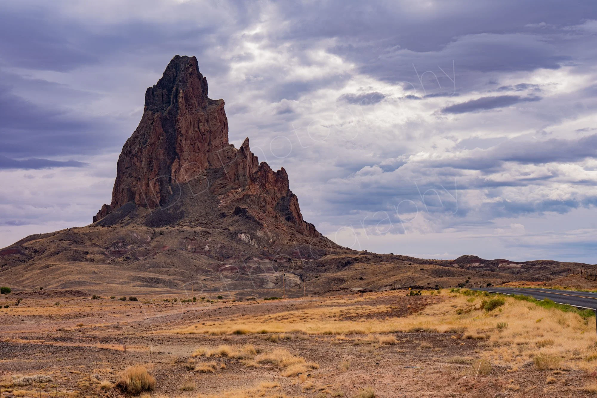 A striking rock formation - El Capitan- emerging from the desert floor under a dramatic cloudy sky in Arizona, USA.
