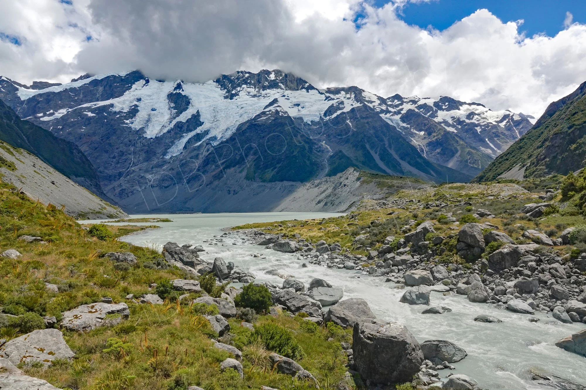 View of River Hooker with Mueller Lake,  snow capped mountains and clouded sky on the Hooker Valley track,  Canterbury, New Zealand.