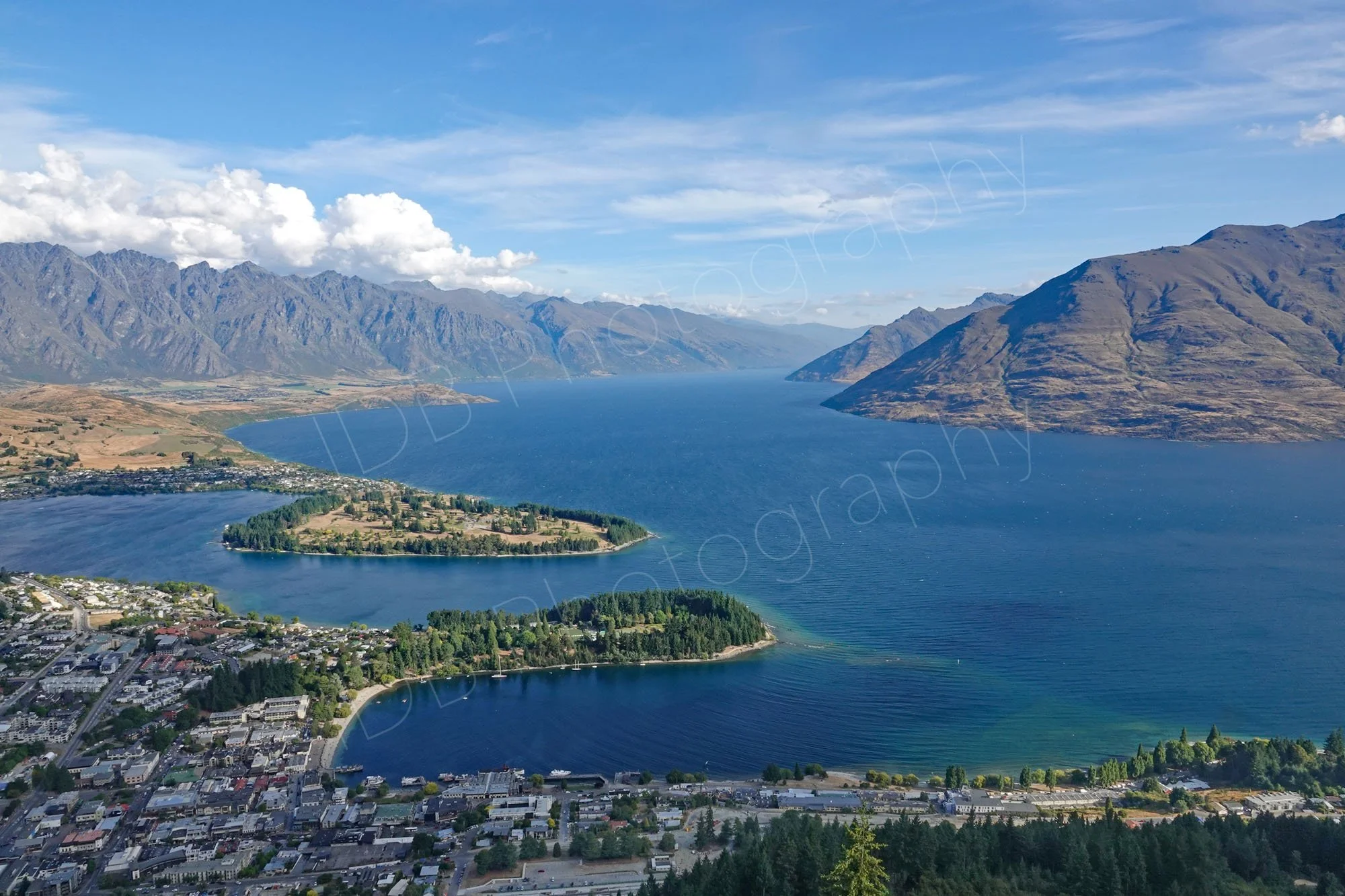Queenstown harbour, Otago, NZ from the top of the Skyline, in sunshine, with the Remarkables and Cecil Peak in the background.
