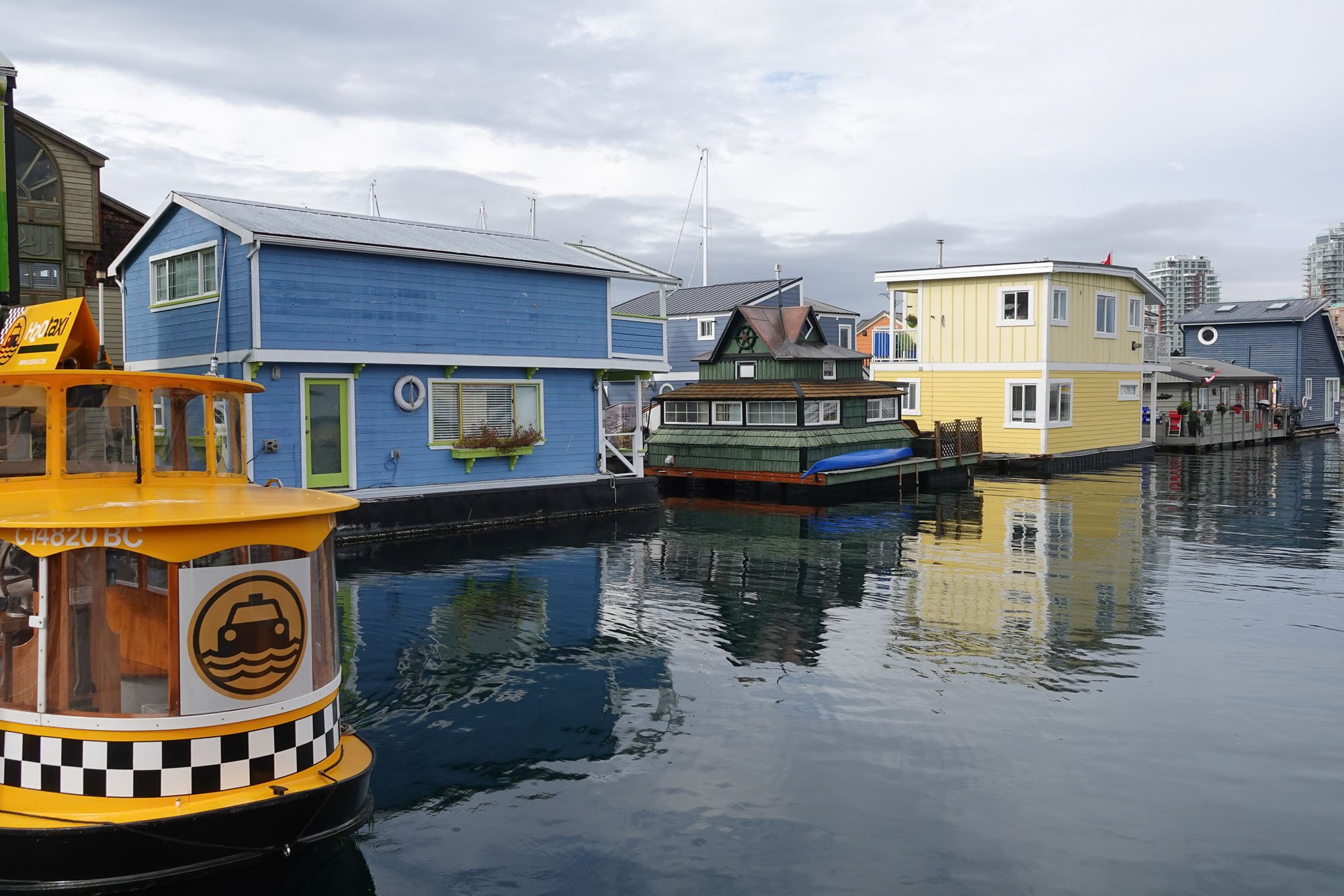 Colourful houseboats and yellow water taxi, Victoria harbour, Vancouver Island, BC, Canada.