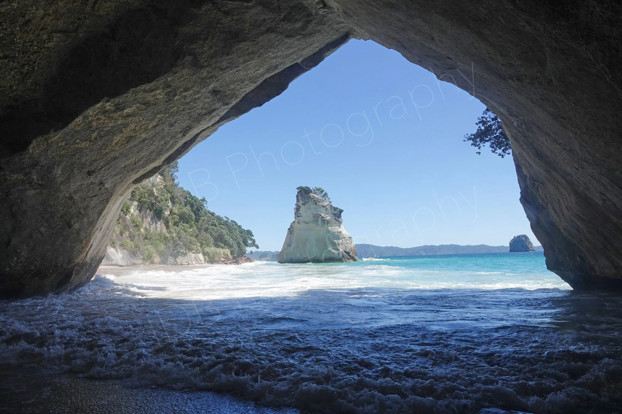 A view through the rocky arch at Cathedral Cove, with Te Hoho Rock in the distance. Coromandel peninsula, New Zealand.
