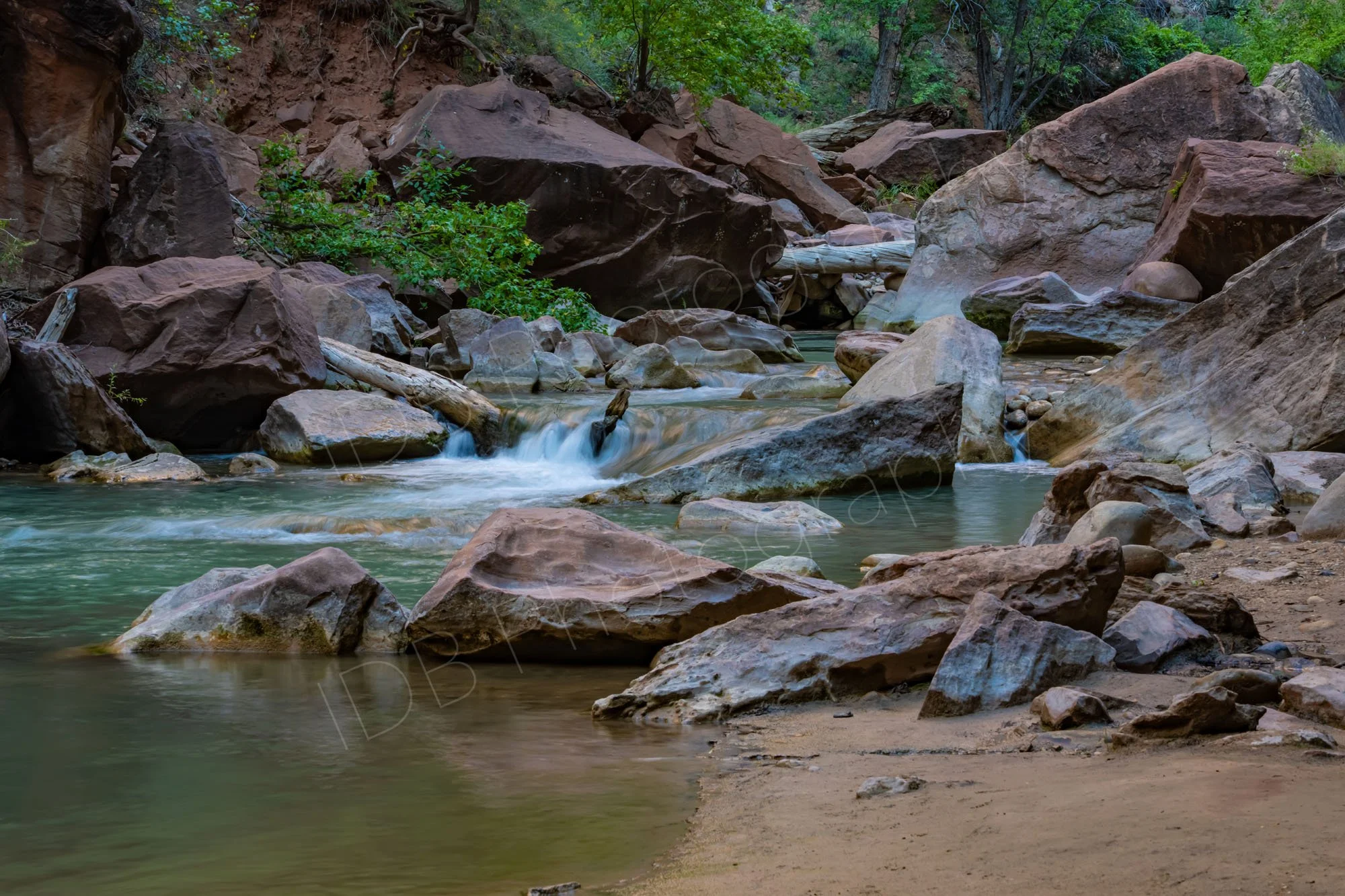 A serene image of a mini waterfall amongst the boulders and fallen trees on the Virgin River, Zion National Park, Utah. 