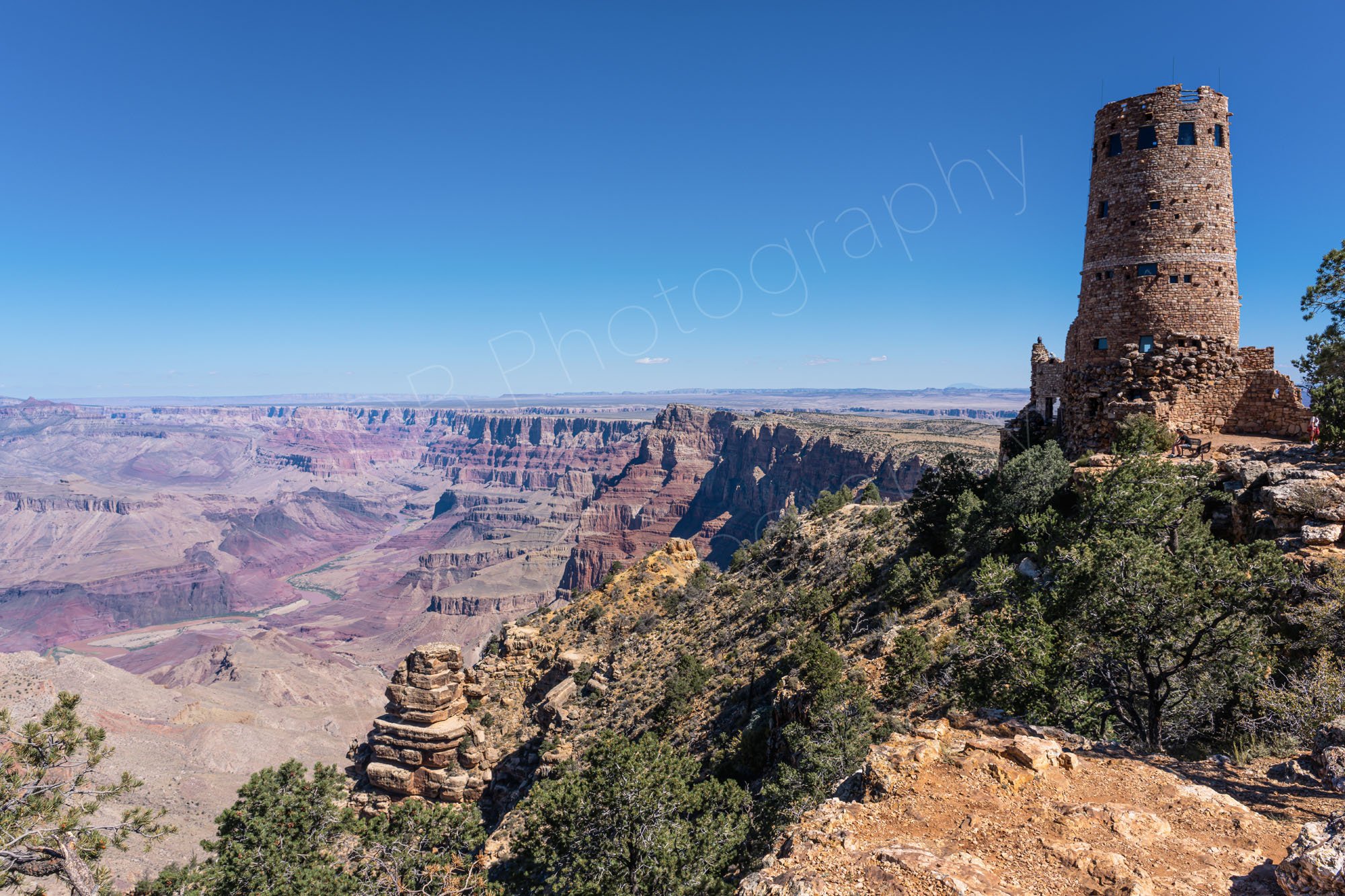 Desert View Watchtower on the rocky edge of the South Rim in Grand Canyon National Park, Arizona, with a blue sky background.