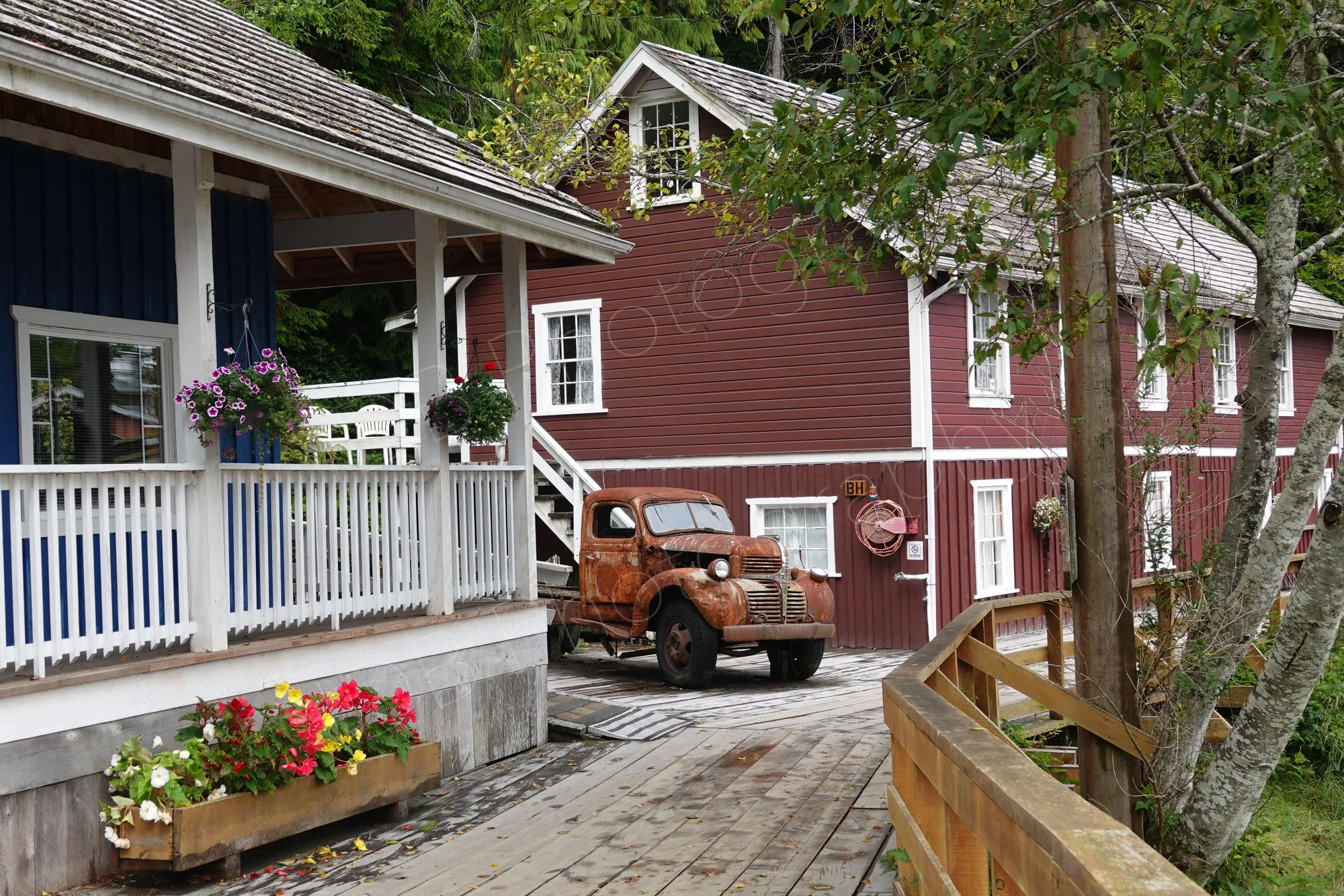 A rusted vintage truck, timbered buildings and boardwalks at the historic hamlet of Telegraph Cove, Vancouver Island, BC, Canada.