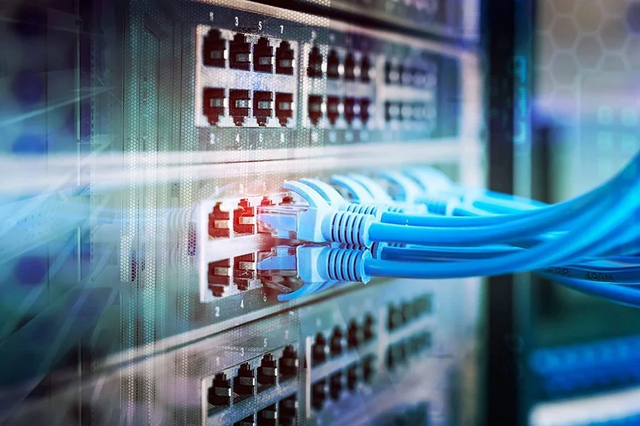 Close-up of a network switch with multiple blue Ethernet cables connected, with blinking LEDs on the switch.