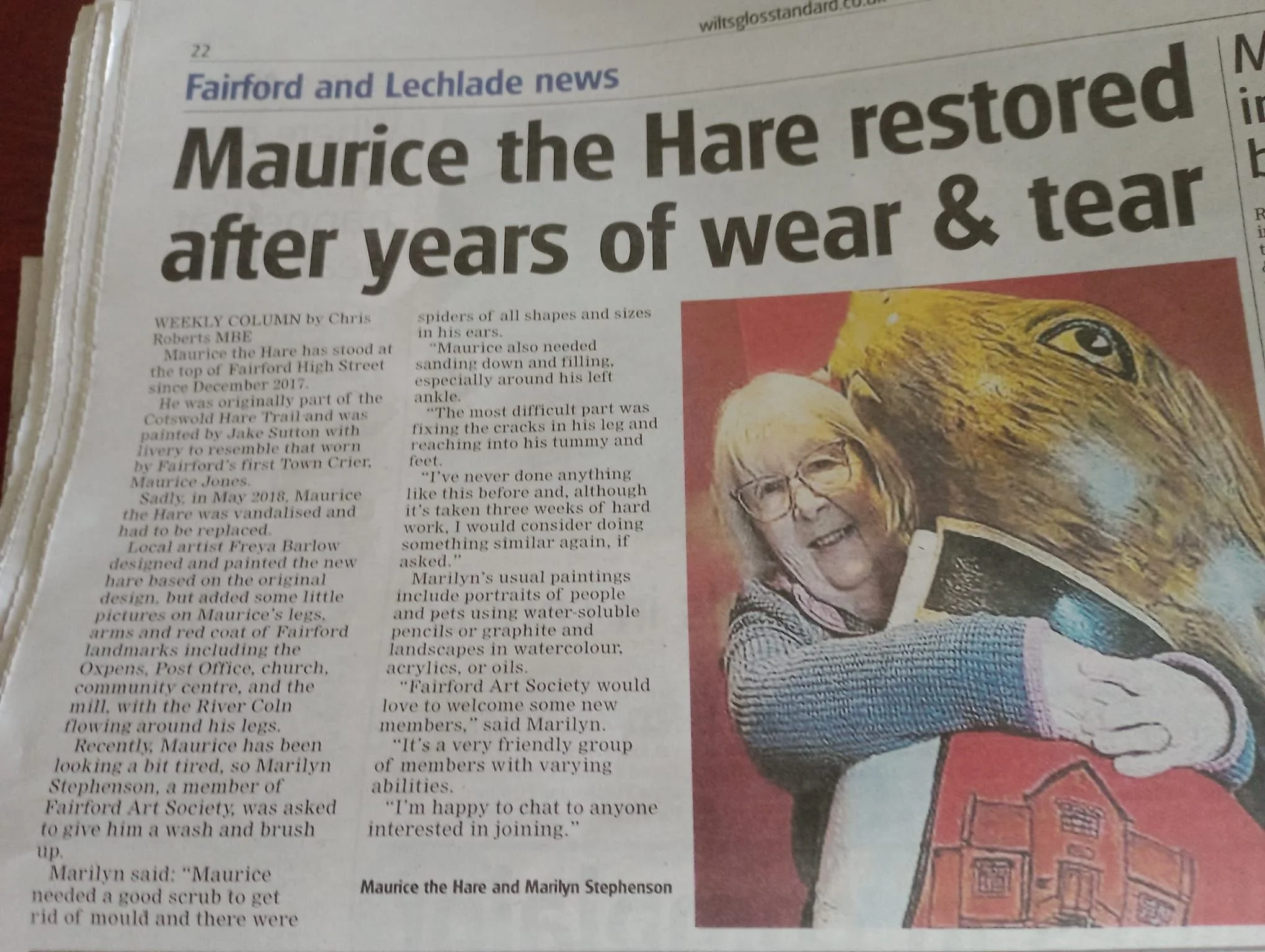 Newspaper article with headline: 'Maurice the Hare restored after years of wear & tear'. Includes a photo of a woman with glasses hugging a large, illustrated hare. The article discusses Maurice the Hare's restoration and the local art society.