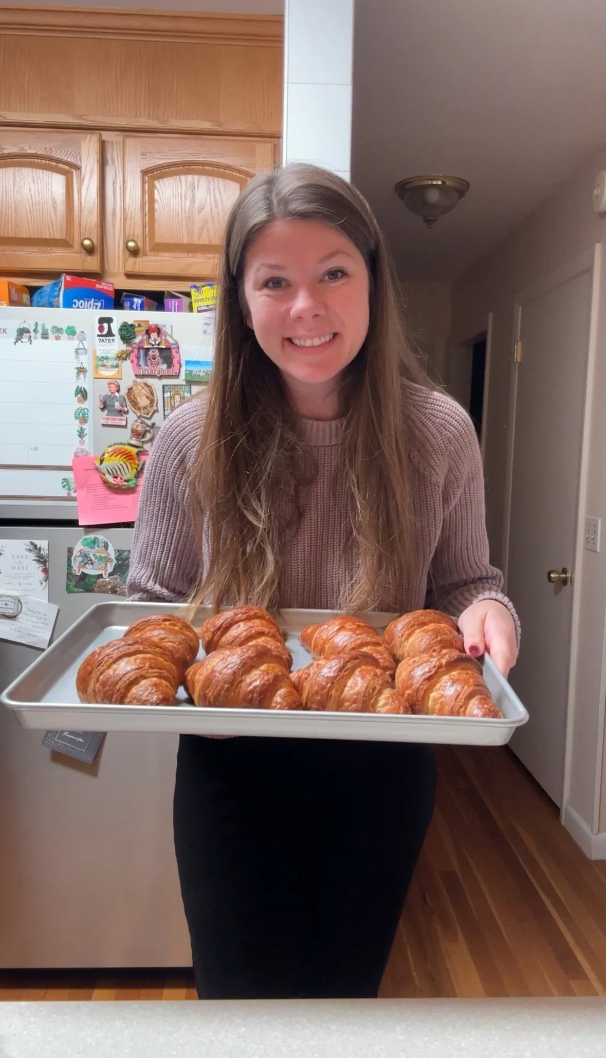 Image of Katy, owner, holding a sheet tray of croissants in her home