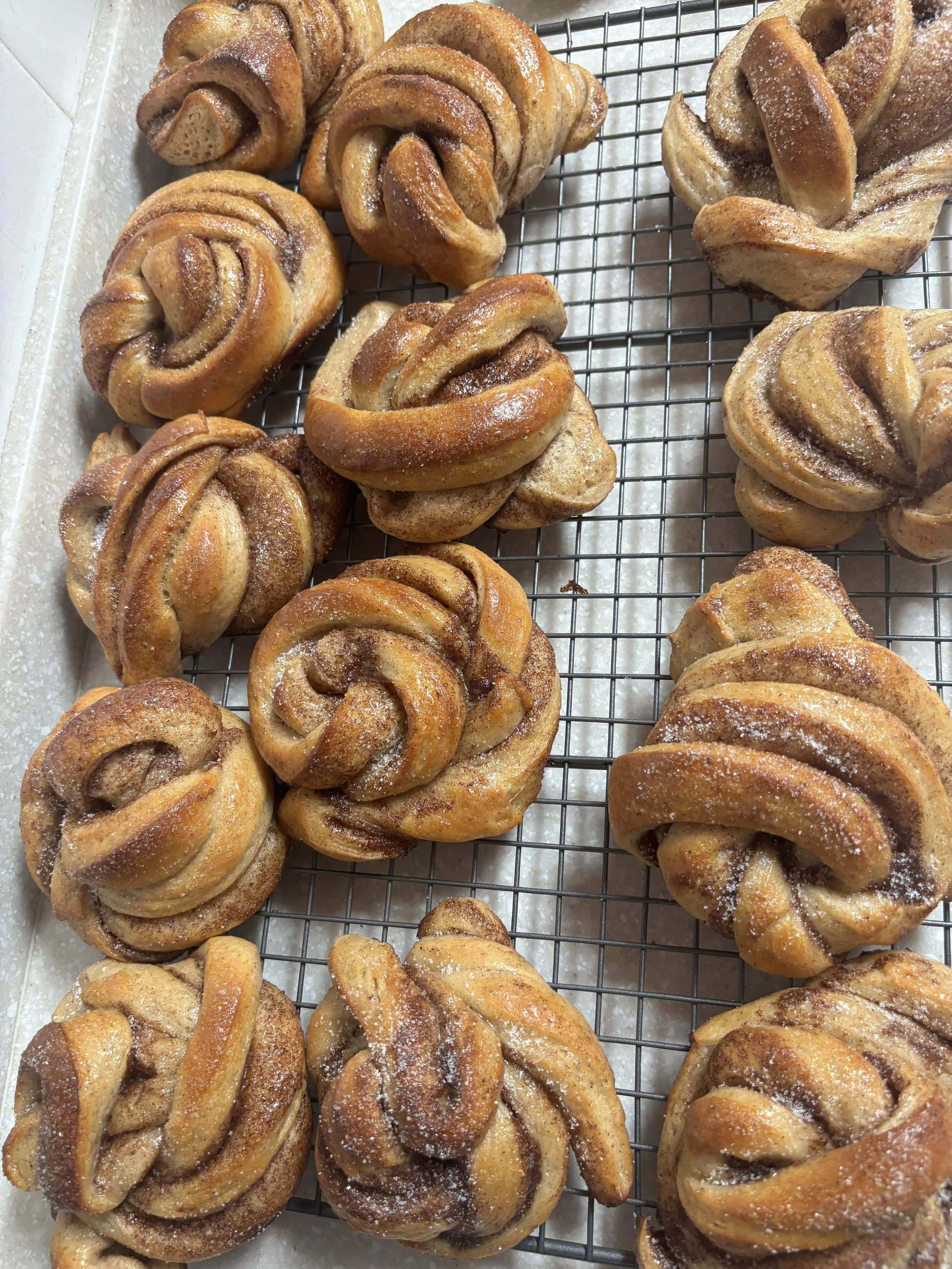 Image of many cinnamon buns on cooling rack