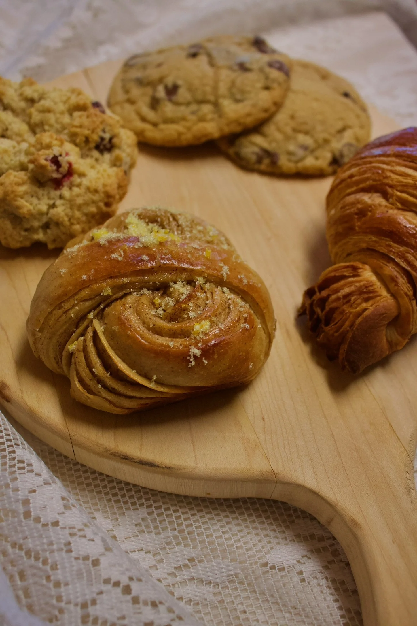 Image of cranberry scone, chocolate chip cookies, croissant, and orange morning bun on cutting board