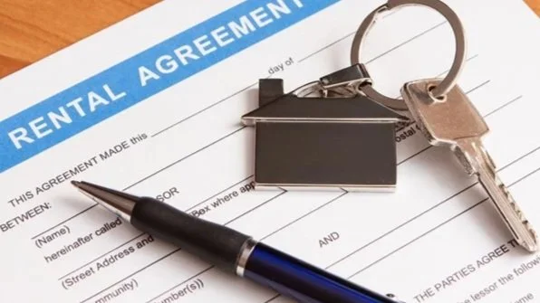 Rental agreement document with a pen, house-shaped keychain, and a silver key on top of it.