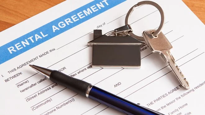 Rental agreement form with a pen, house-shaped keychain, and a key on top.