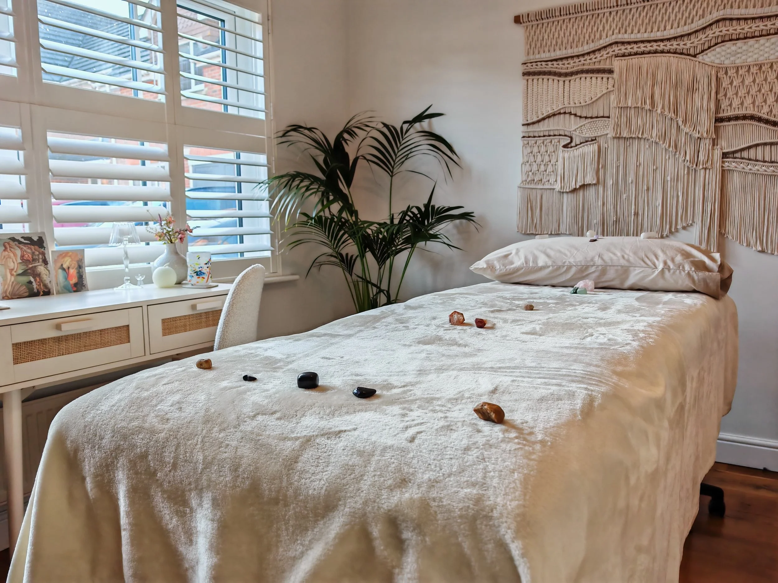 Divine Reiki's practice room, with the bed surrounded by tapestry, crystals and a plant.