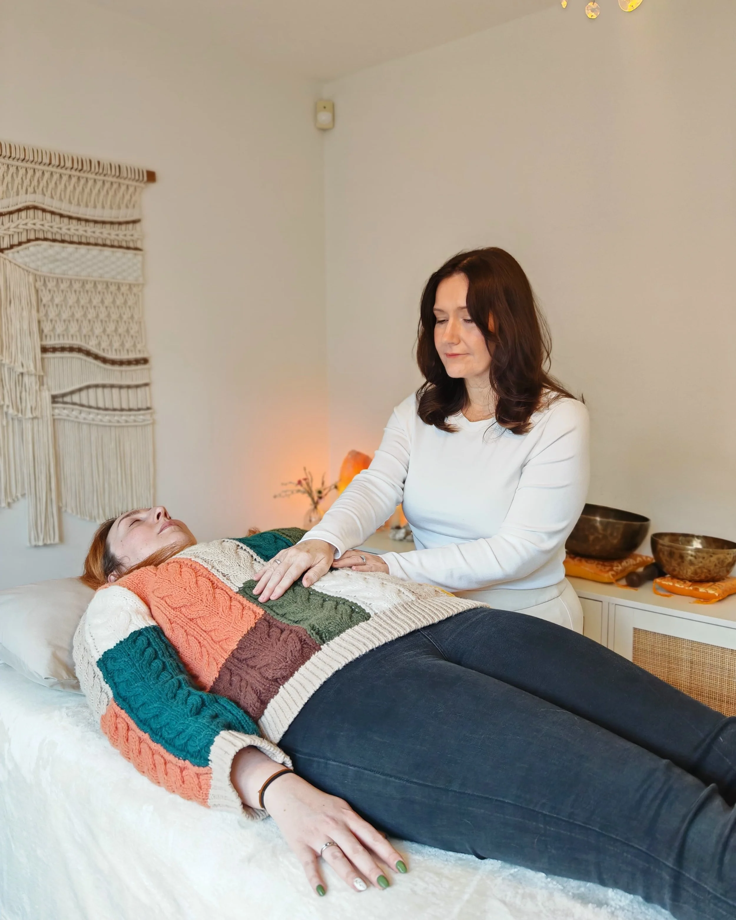 A client of Divine Reiki receiving energy healing from a practitioner, Jill during a session.