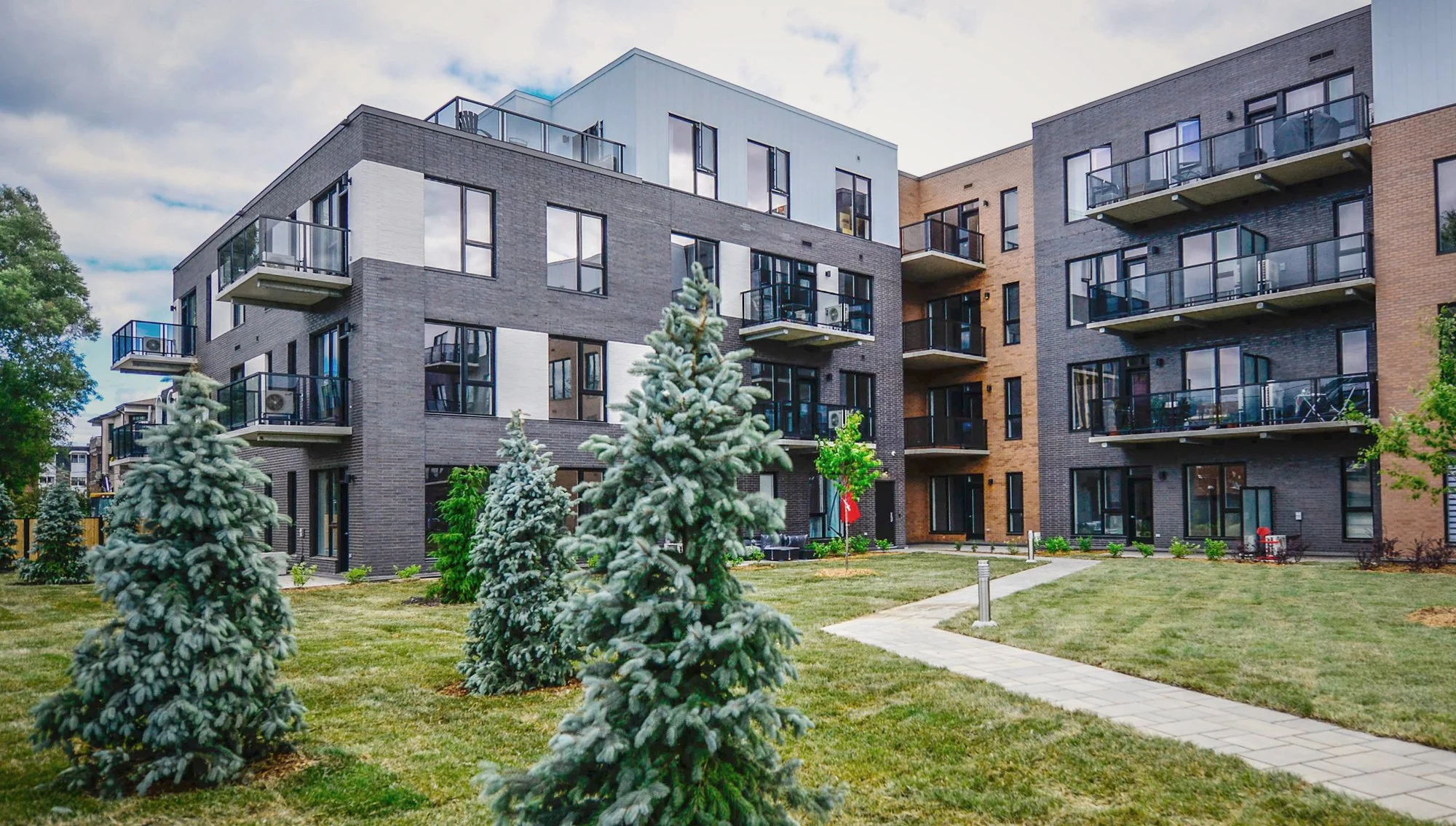 Vue d'un immeuble résidentiel moderne avec balcon, arbres et jardin