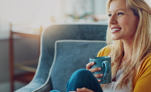 Femme souriante qui tient une tasse bleue
